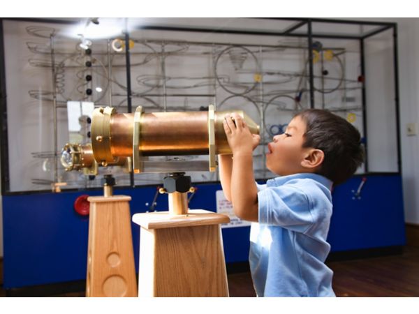 Small child looking through telescope at a museum