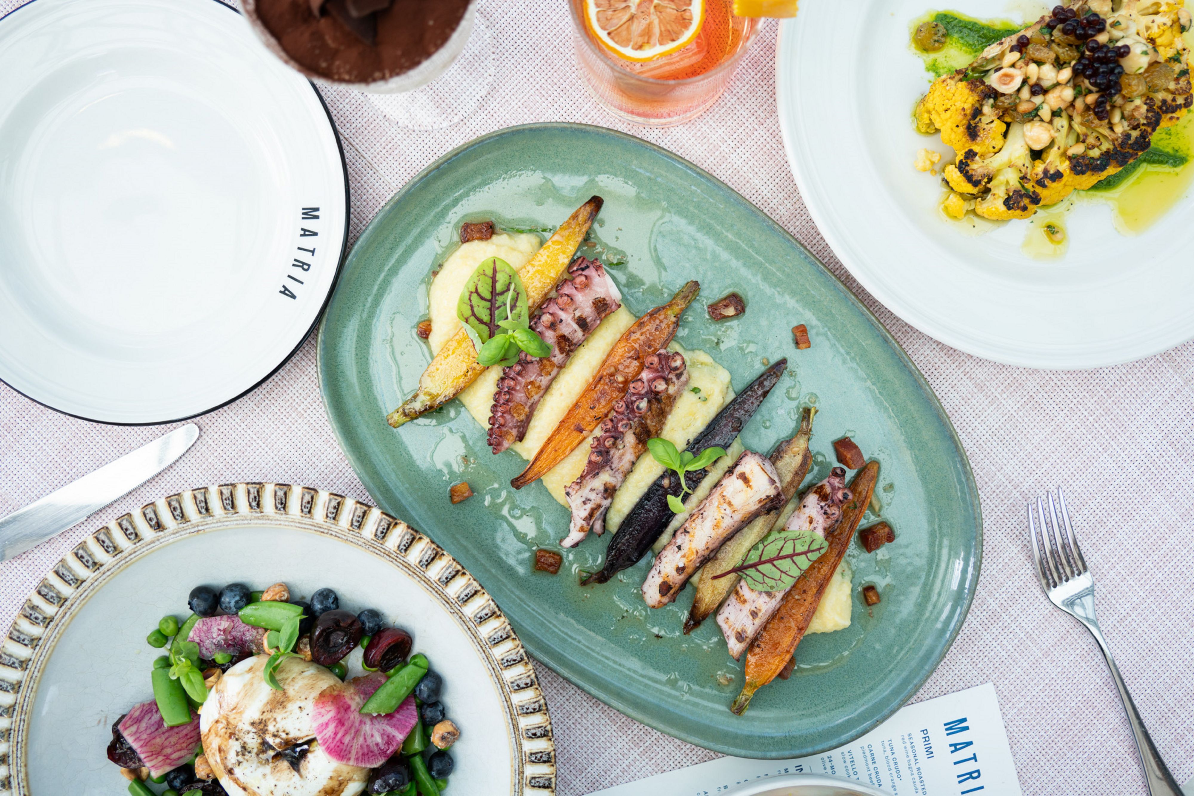 Fresh seafood and vegetables on colorful plates from Matria restaurant 