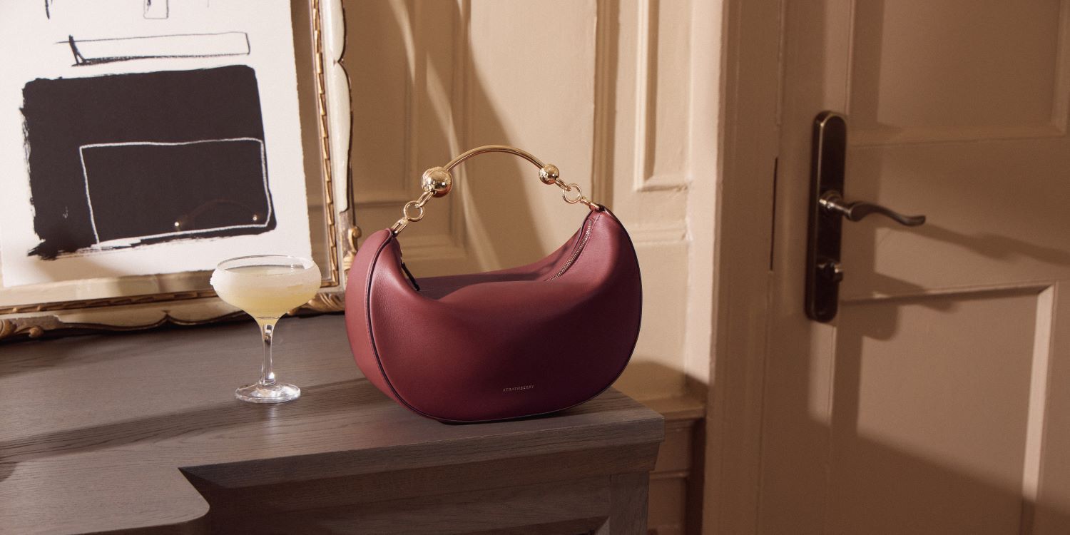 Red Strathberry handbag next to a cocktail