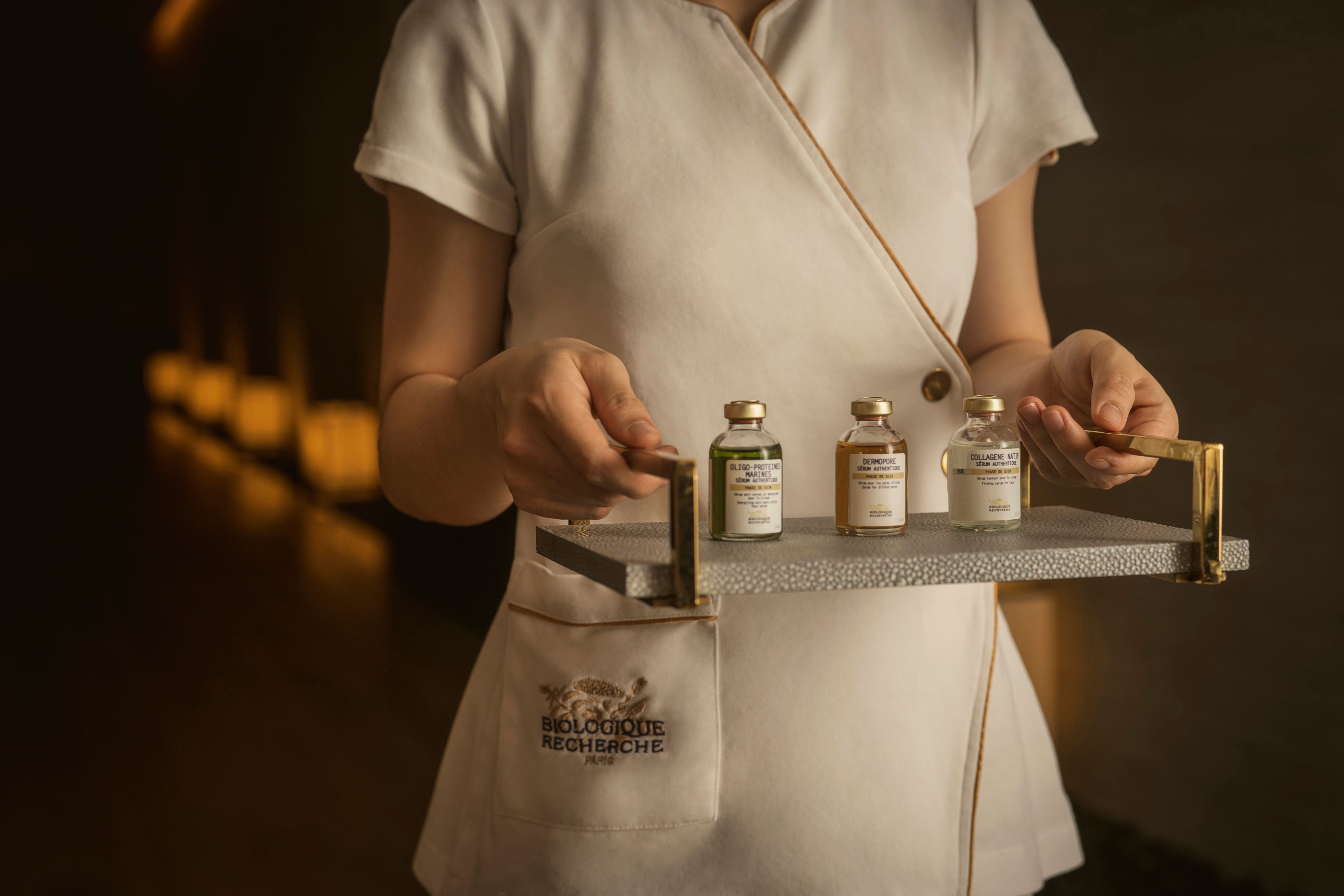 Therapist holding a tray with skincare bottles displayed