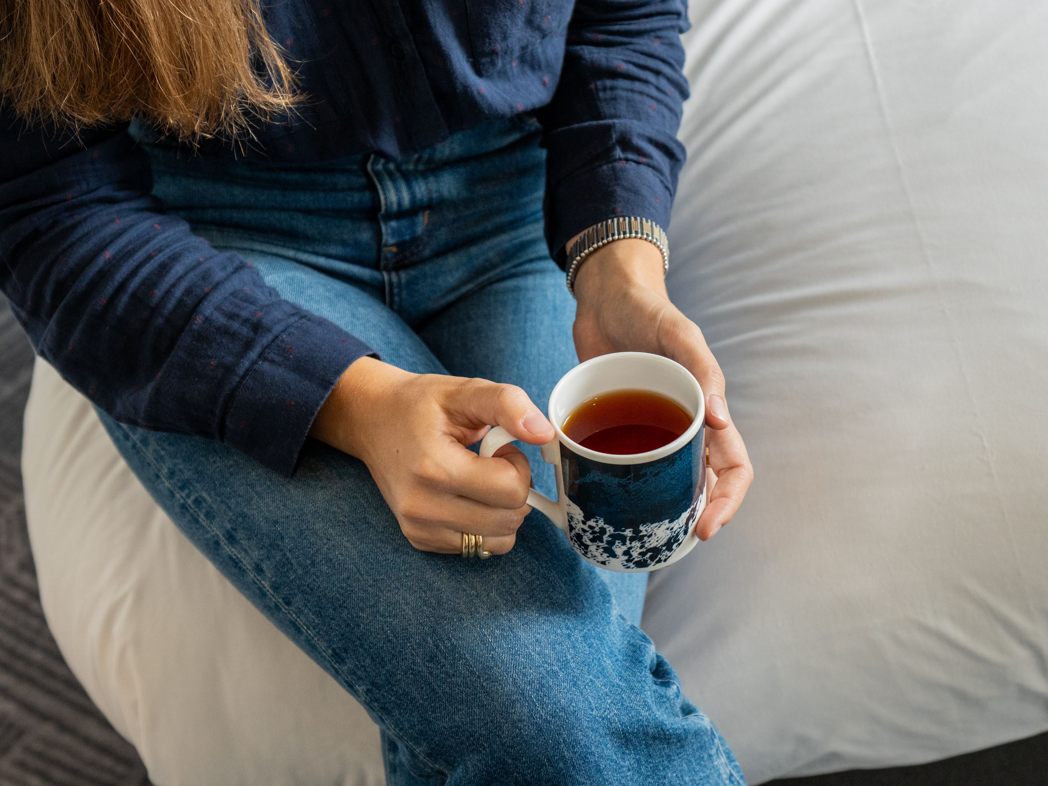 Guest with coffee on hotel bed