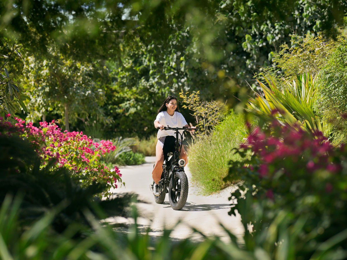 Woman riding bicycle through lush garden