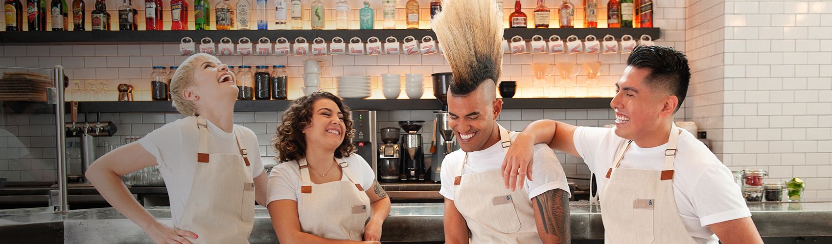 four kitchen staff laughing behind counter in kitchen