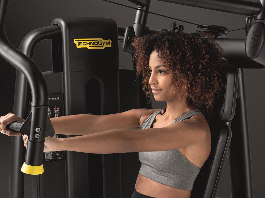 Woman using chest press machine at hotel fitness centre