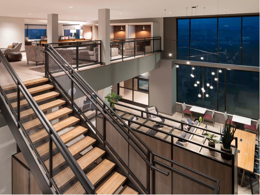 Two-storey lobby with co-working tables and booths upstairs.