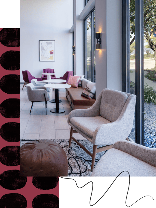 Modern lounge area with chairs, table and large windows.