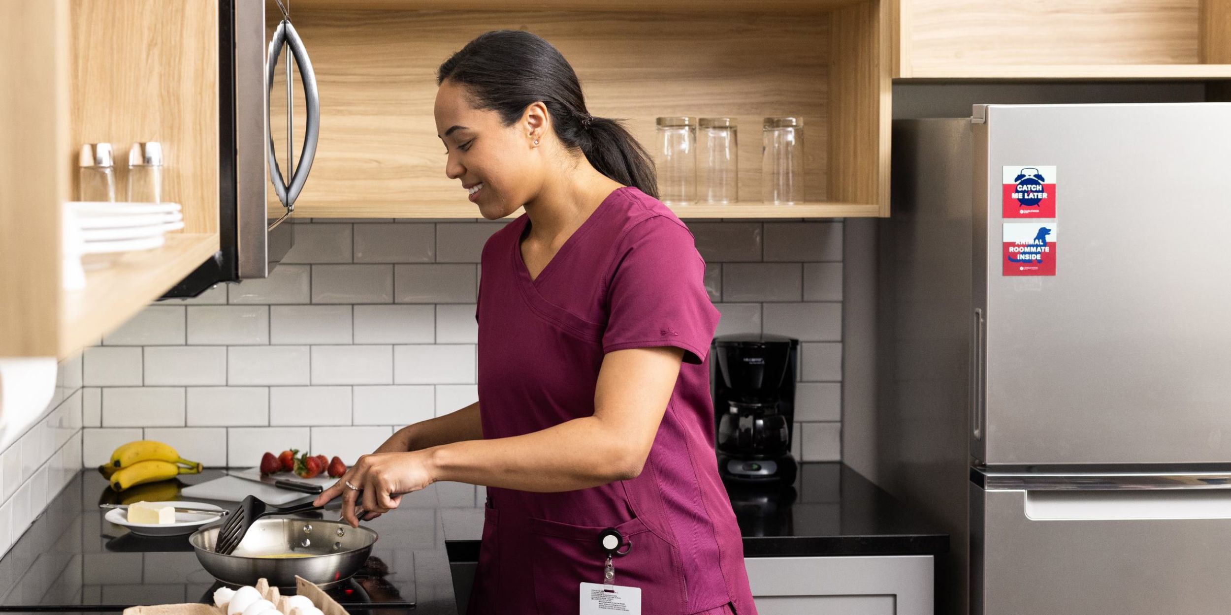 A guest in a suite kitchen cooking with ingredients on the counter top 