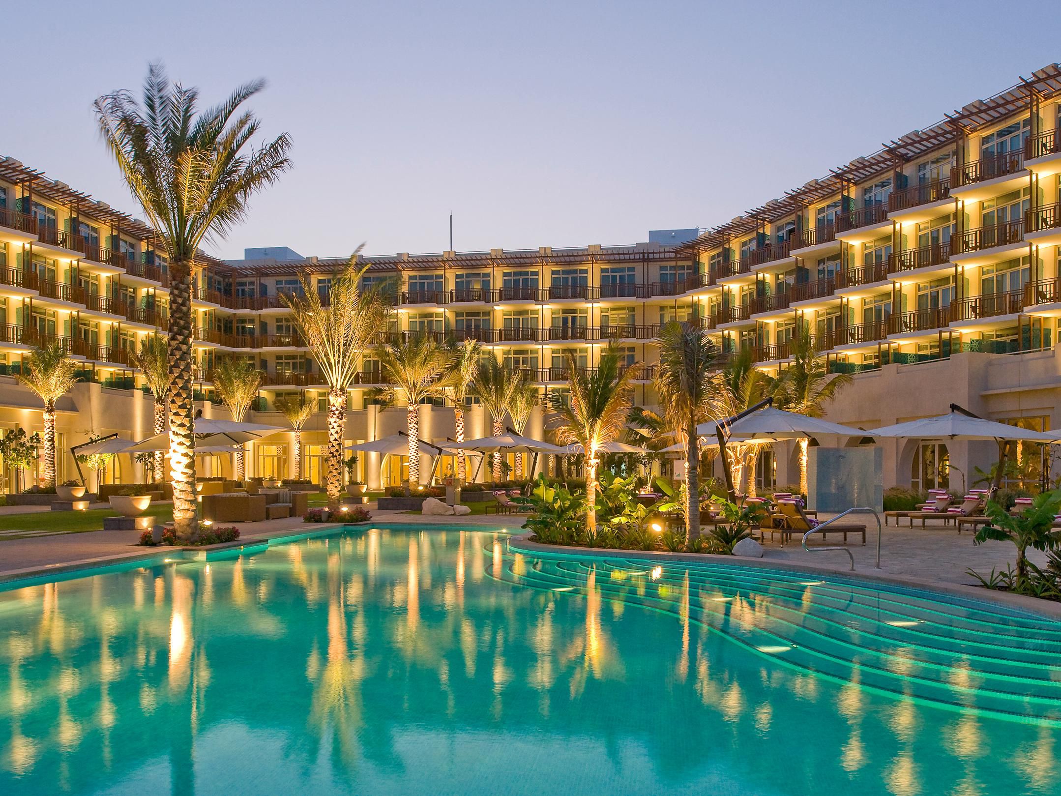 The lounge pool at dusk lit by the hotel behind.