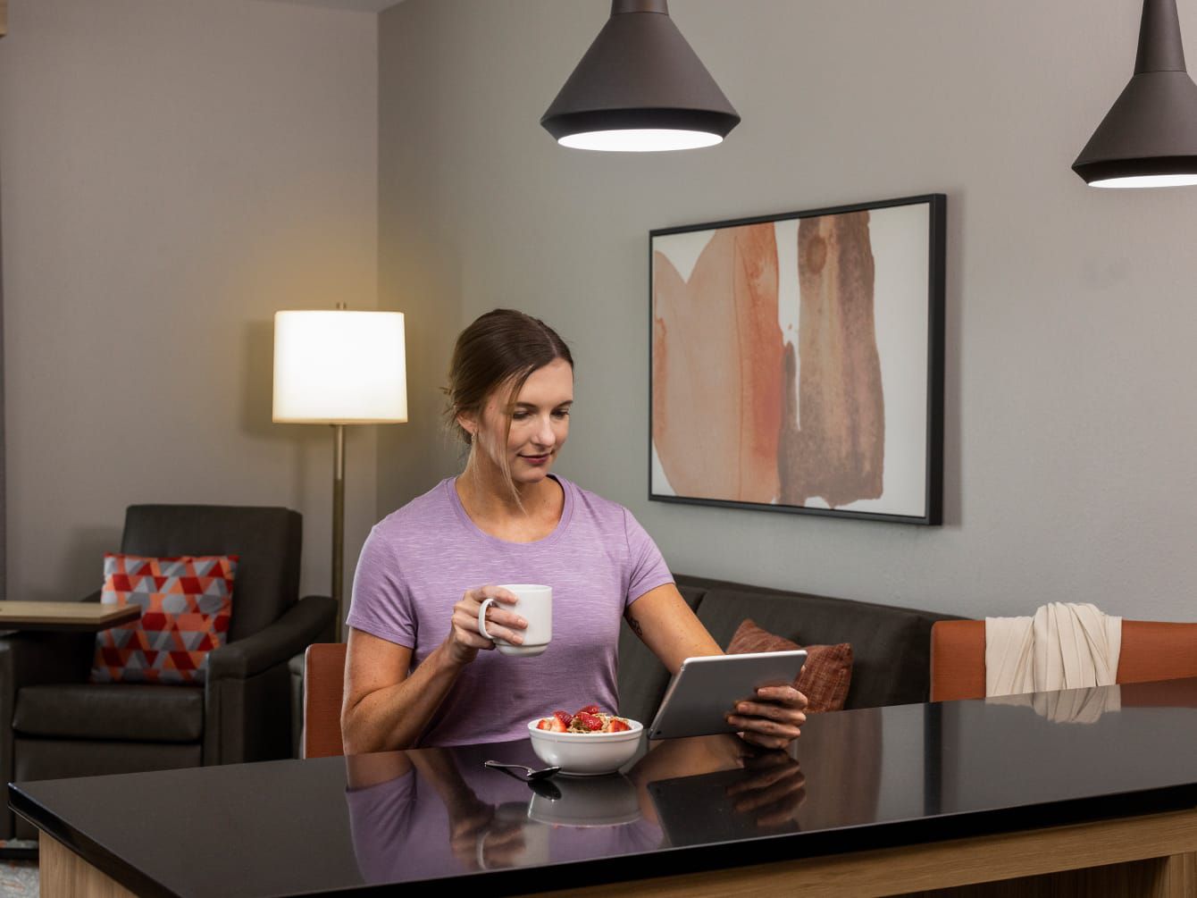 Woman eating breakfast and looking at tablet