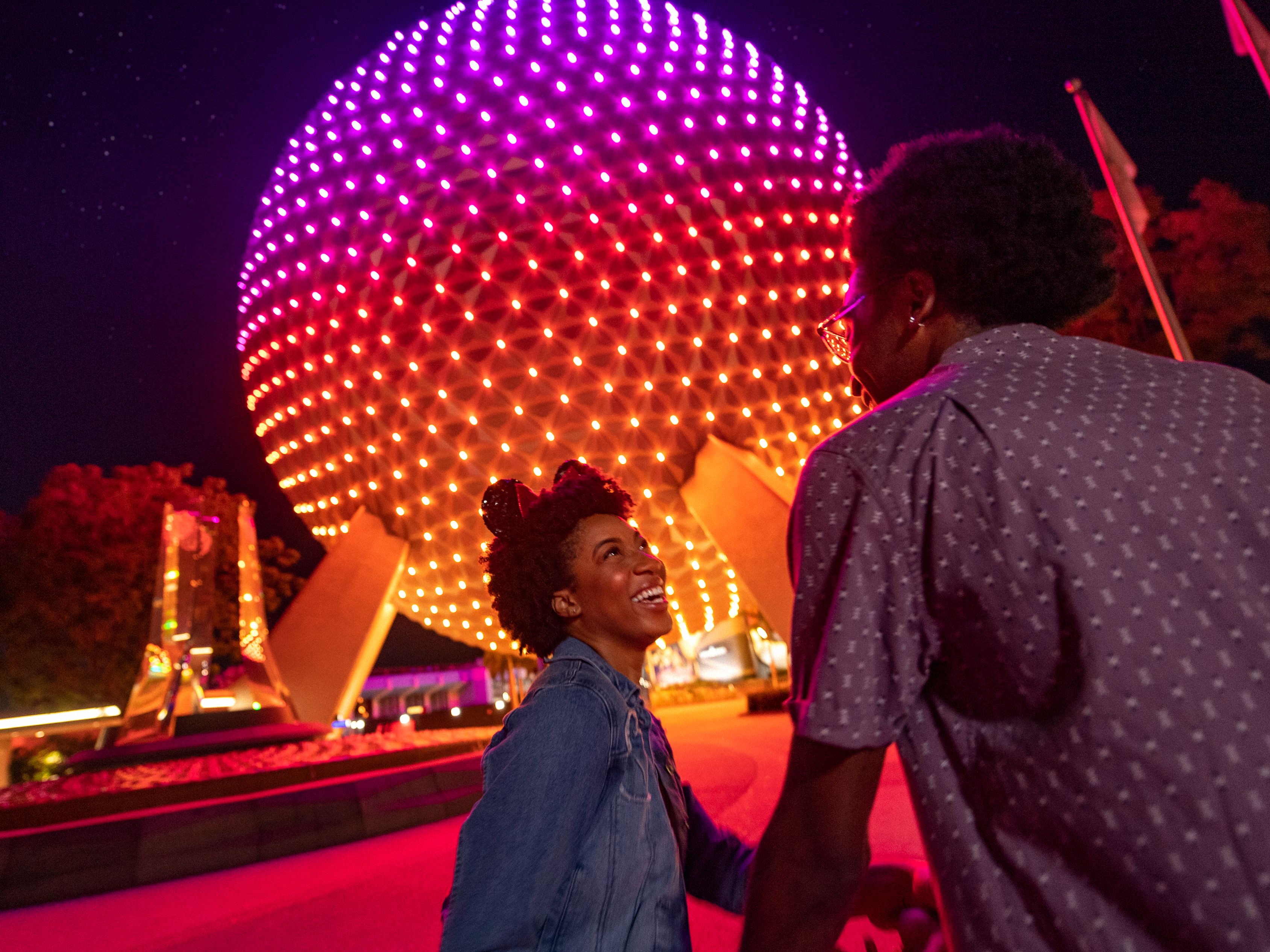 Family standing in front of Epcot Center at night