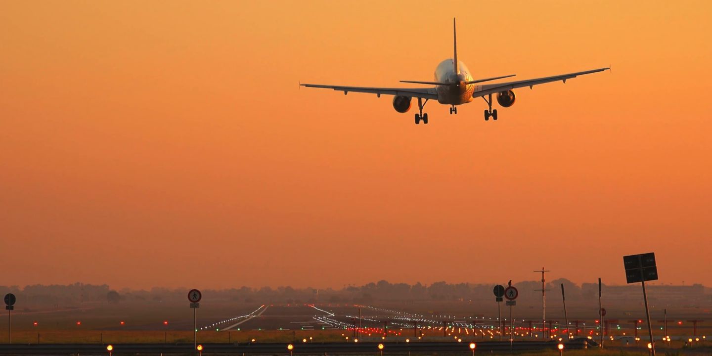 Plane landing on runway at sunset