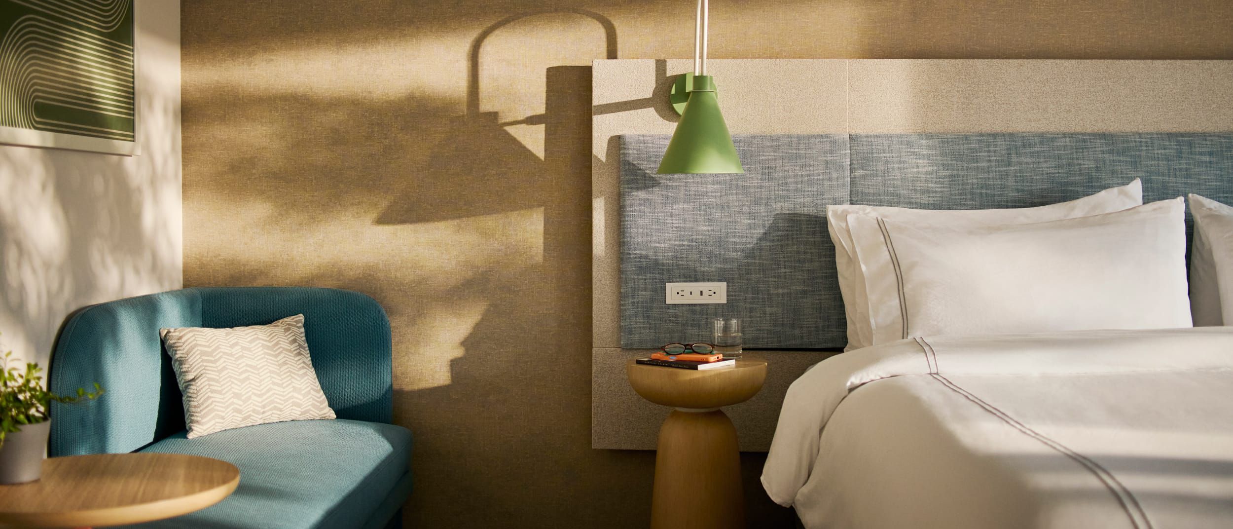 Modern hotel room with crisp white bedding and shadows cast on the wall.