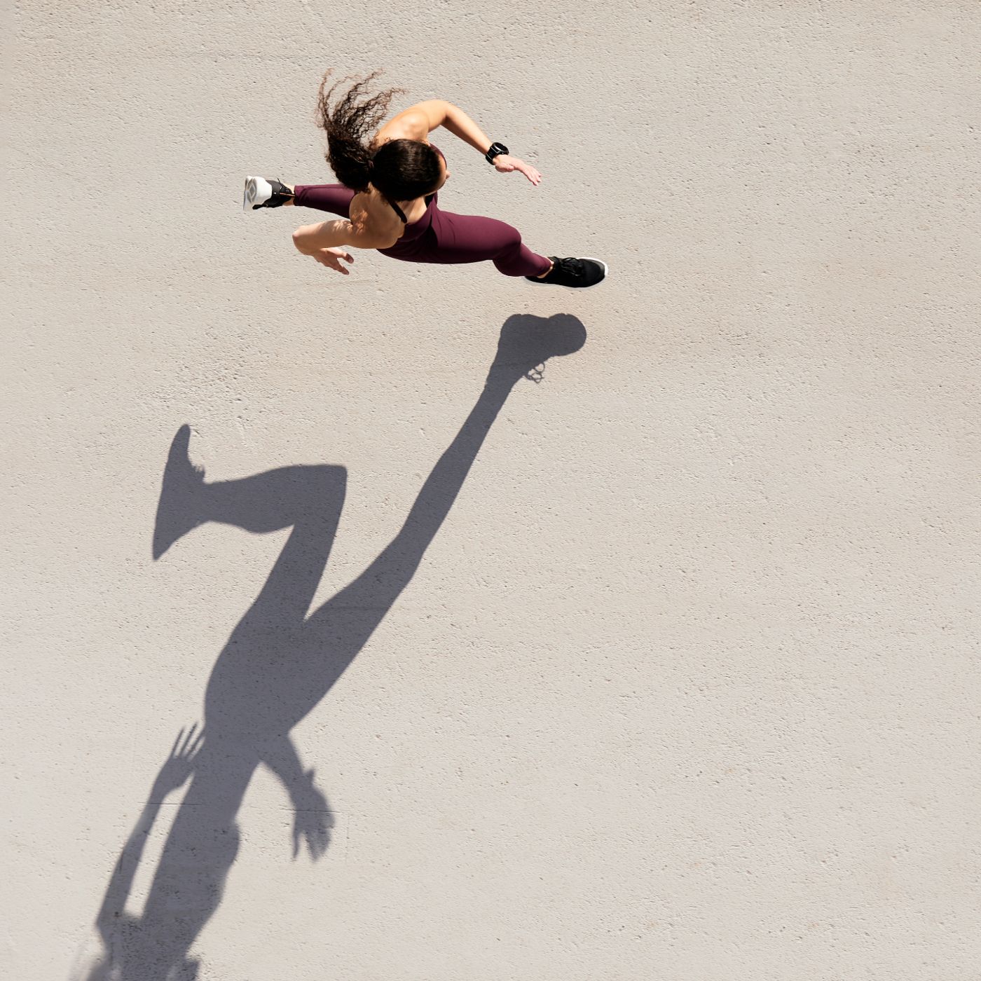 Top down view of woman running with shadow beside her