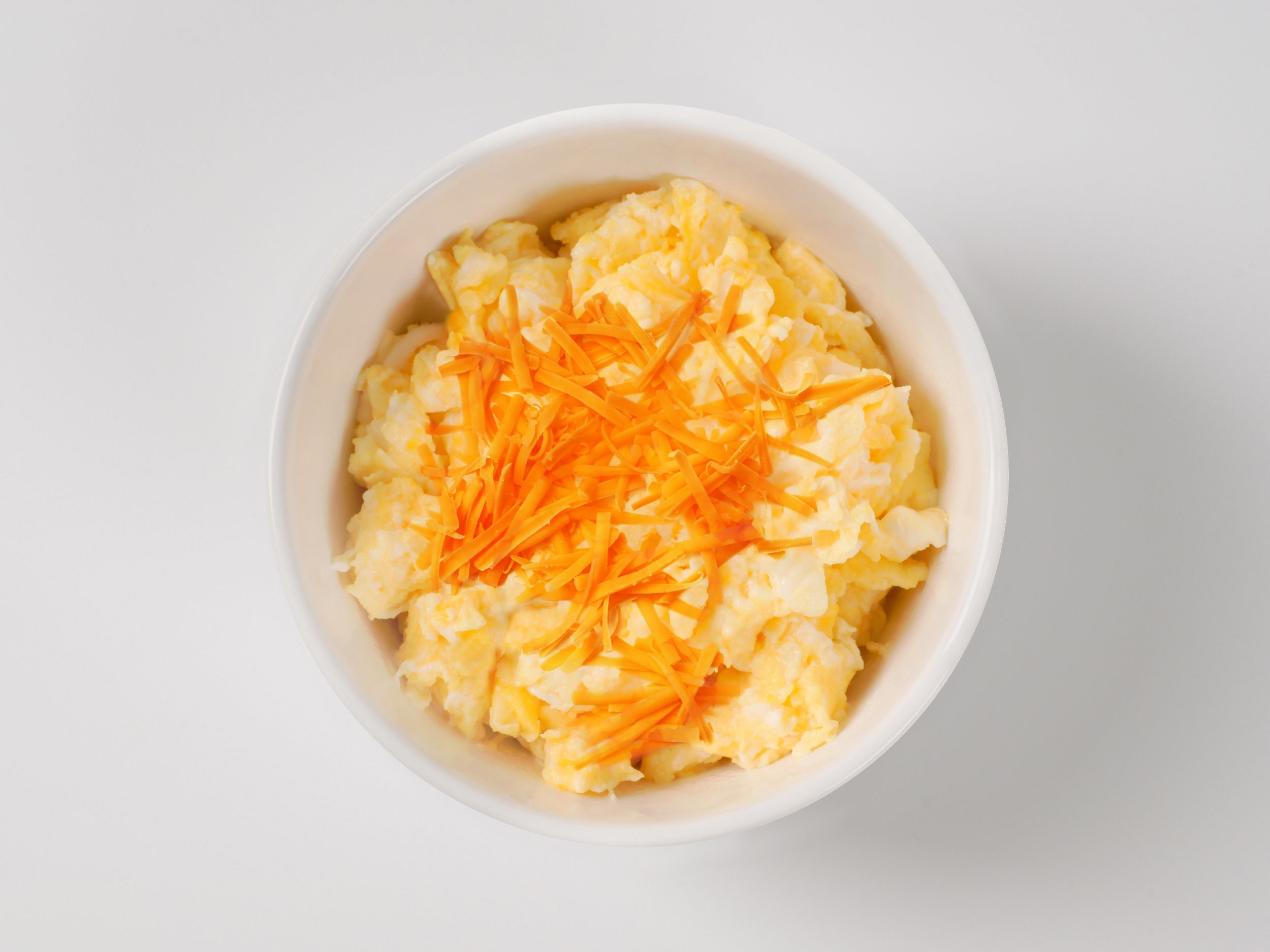 Top view of a bowl of scrambled eggs sprinkled with cheese