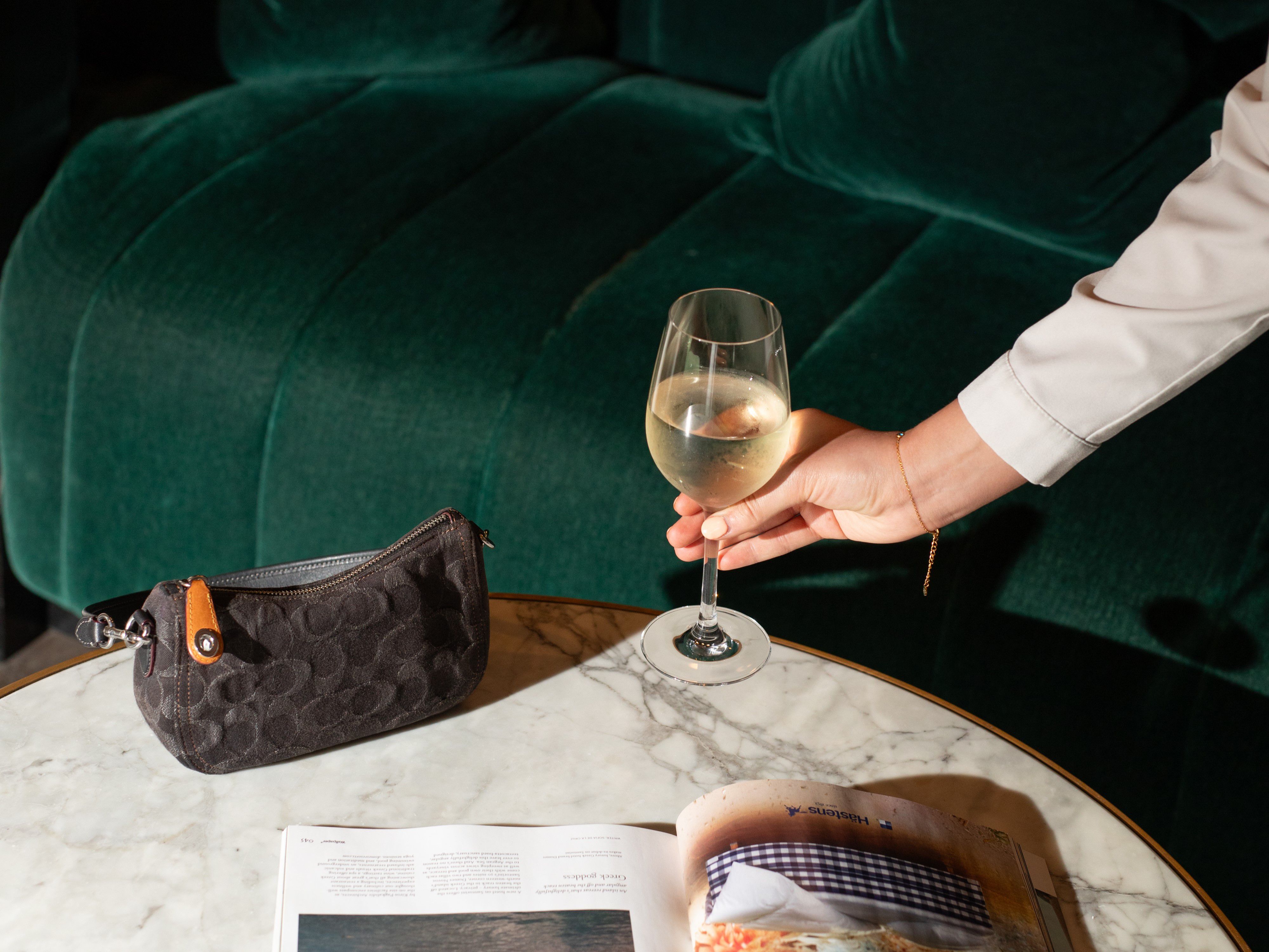 A hand placing a wine glass on a table