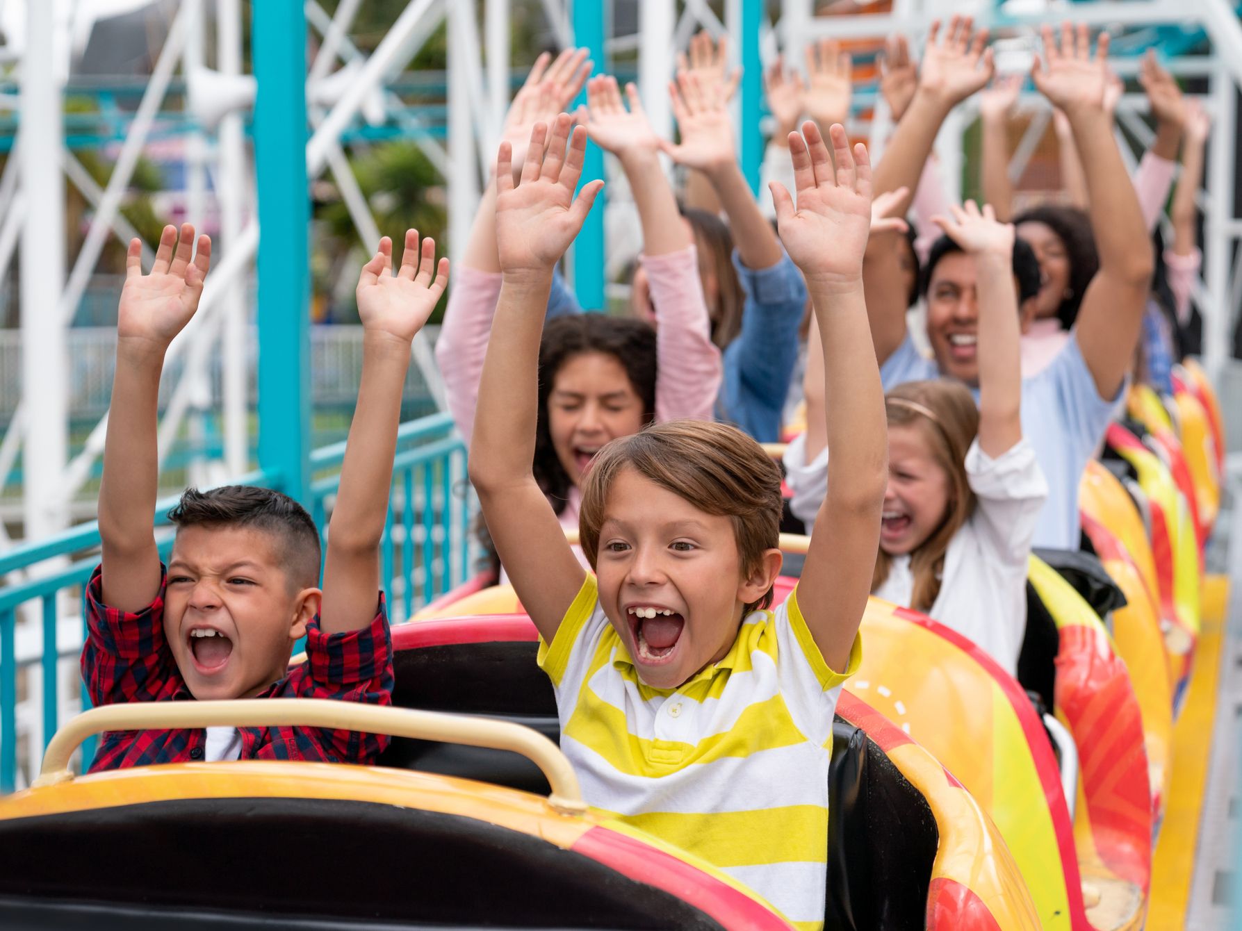 Kids with their hands up in a roller coaster
