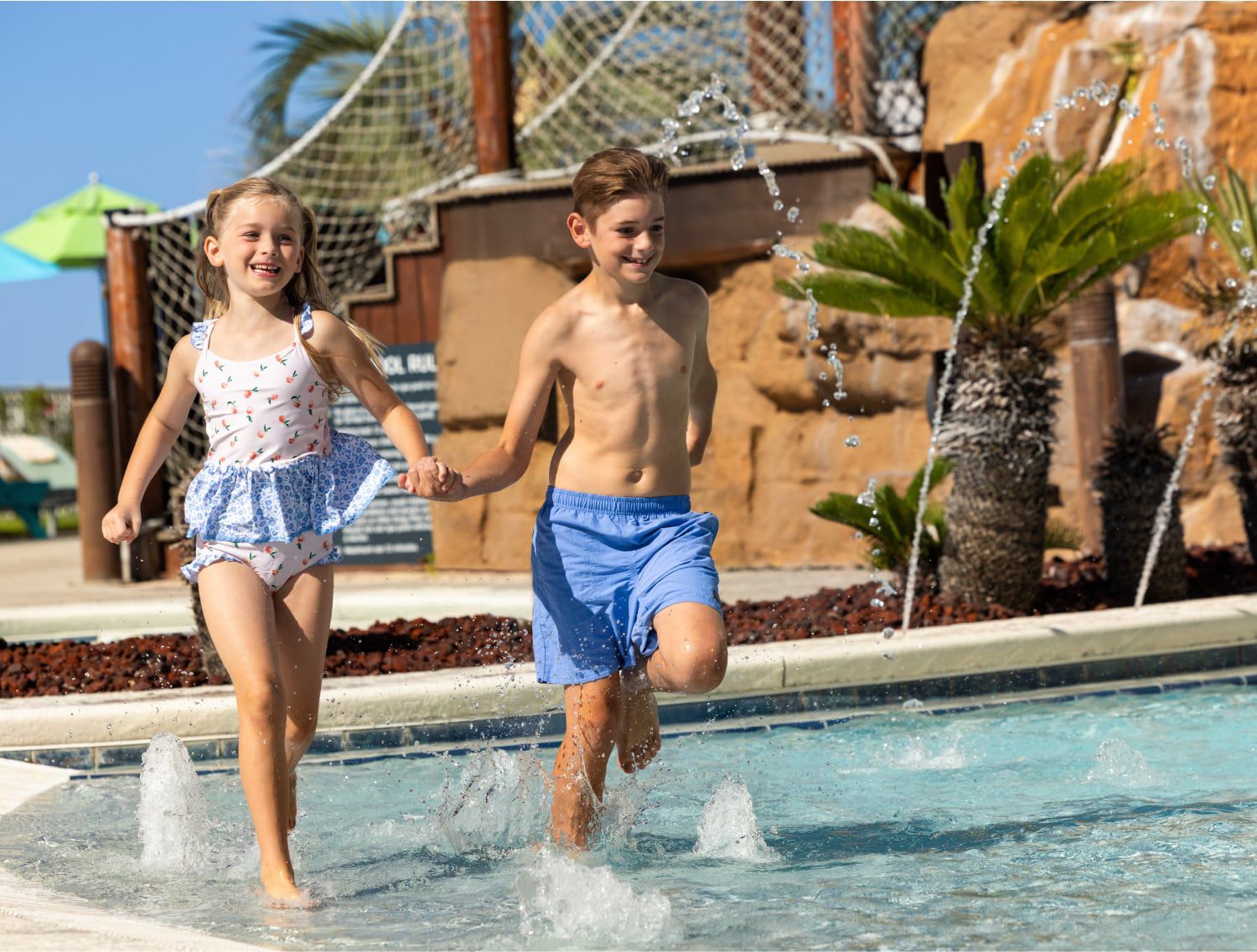 两名孩童手拉手在水上乐园玩耍嬉戏