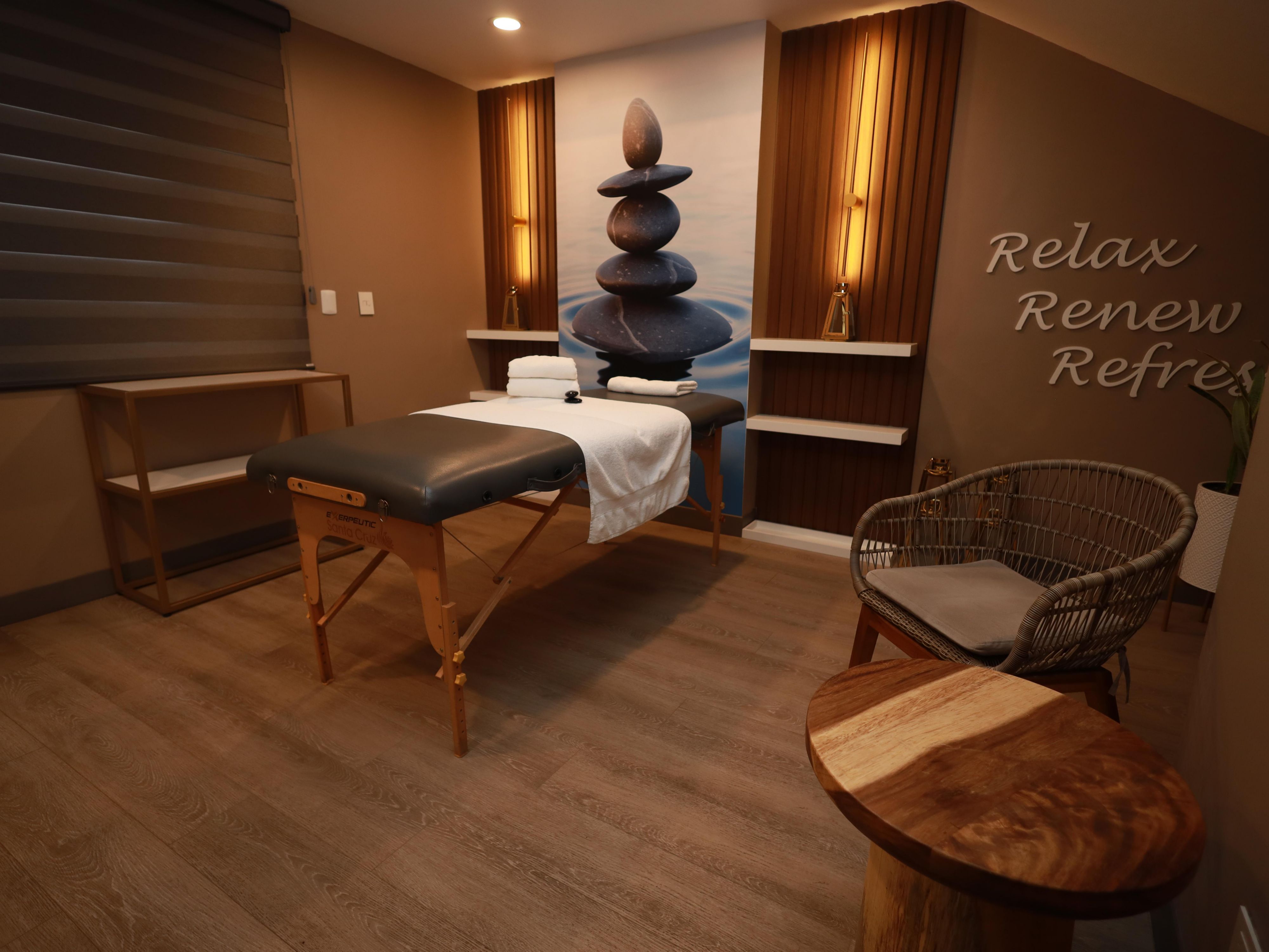 A corner designed for rest and tranquility, with a therapeutic table, warm lighting, and details that evoke serenity, such as Zen stones and minimalist decoration. This spa offers a welcoming atmosphere, perfect for relaxing, renewing, and refreshing body and mind, with style and harmony.