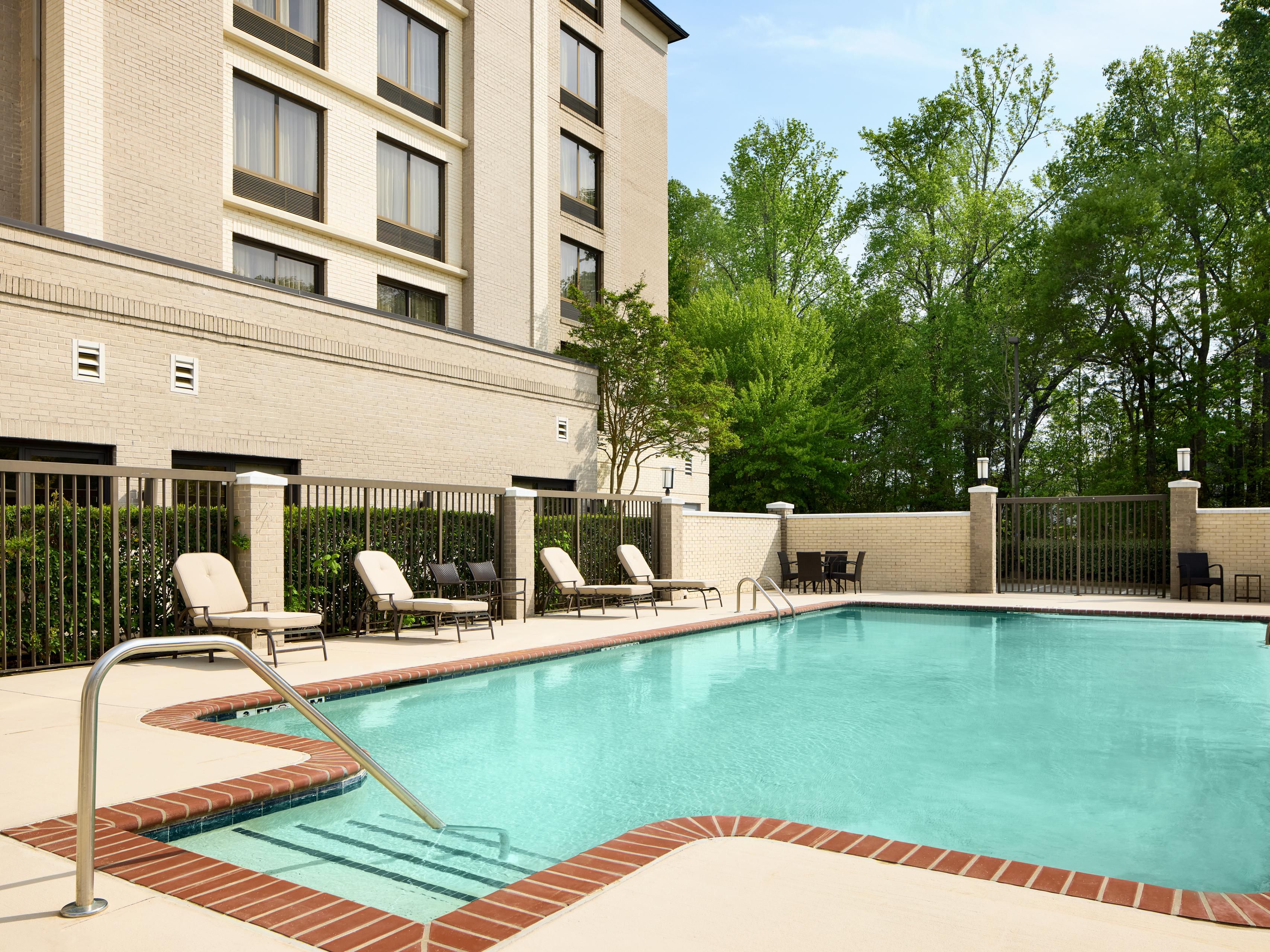 A nice outdoor pool with lounge chairs on a patio.
