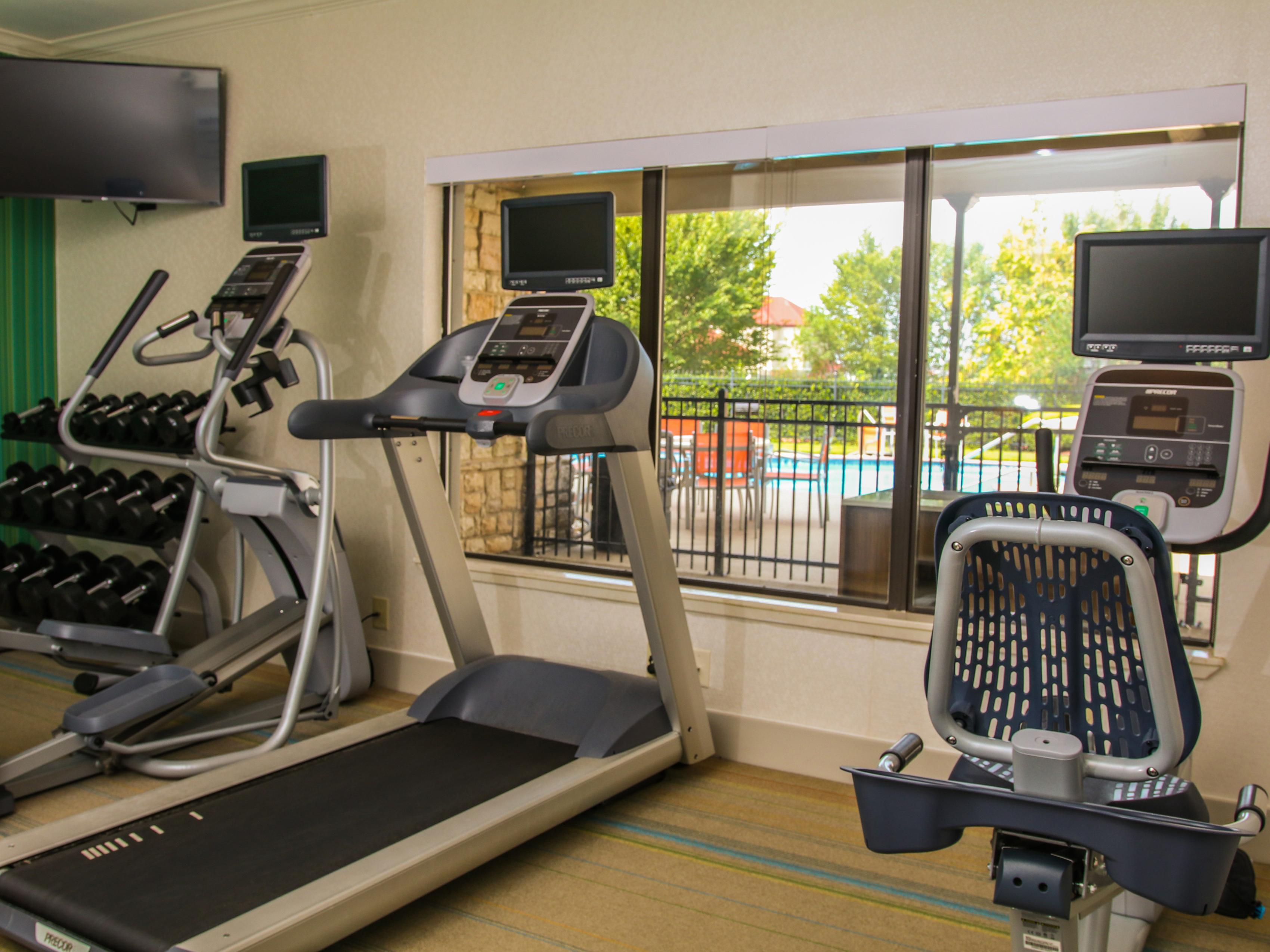 Fitness Center with treadmill looking out to the pool, exercise bike, cardio bike, dumbbells, stretch rope,  & yoga ball with mat.