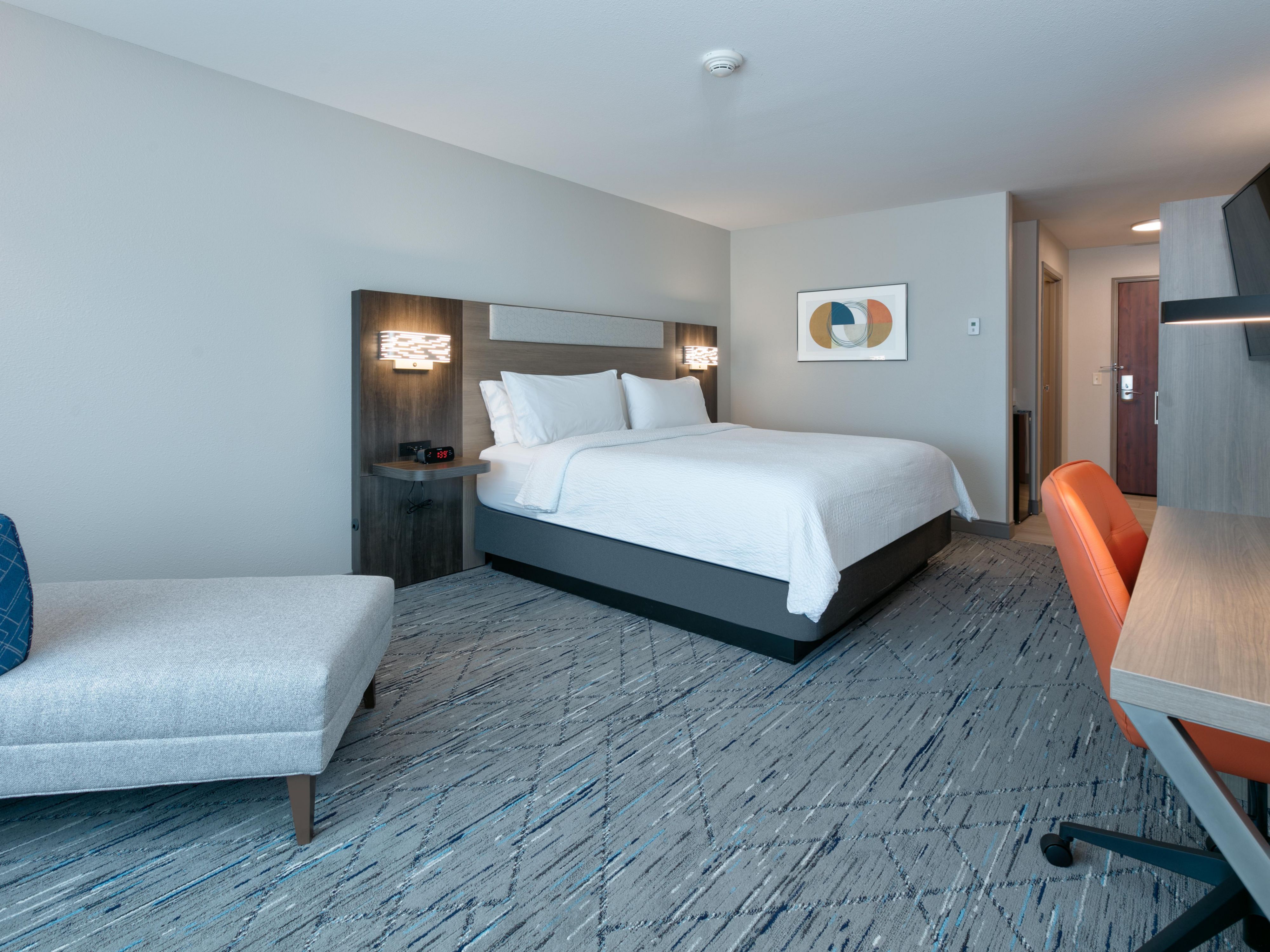 Standard king bed room with large work desk and leisure chair.