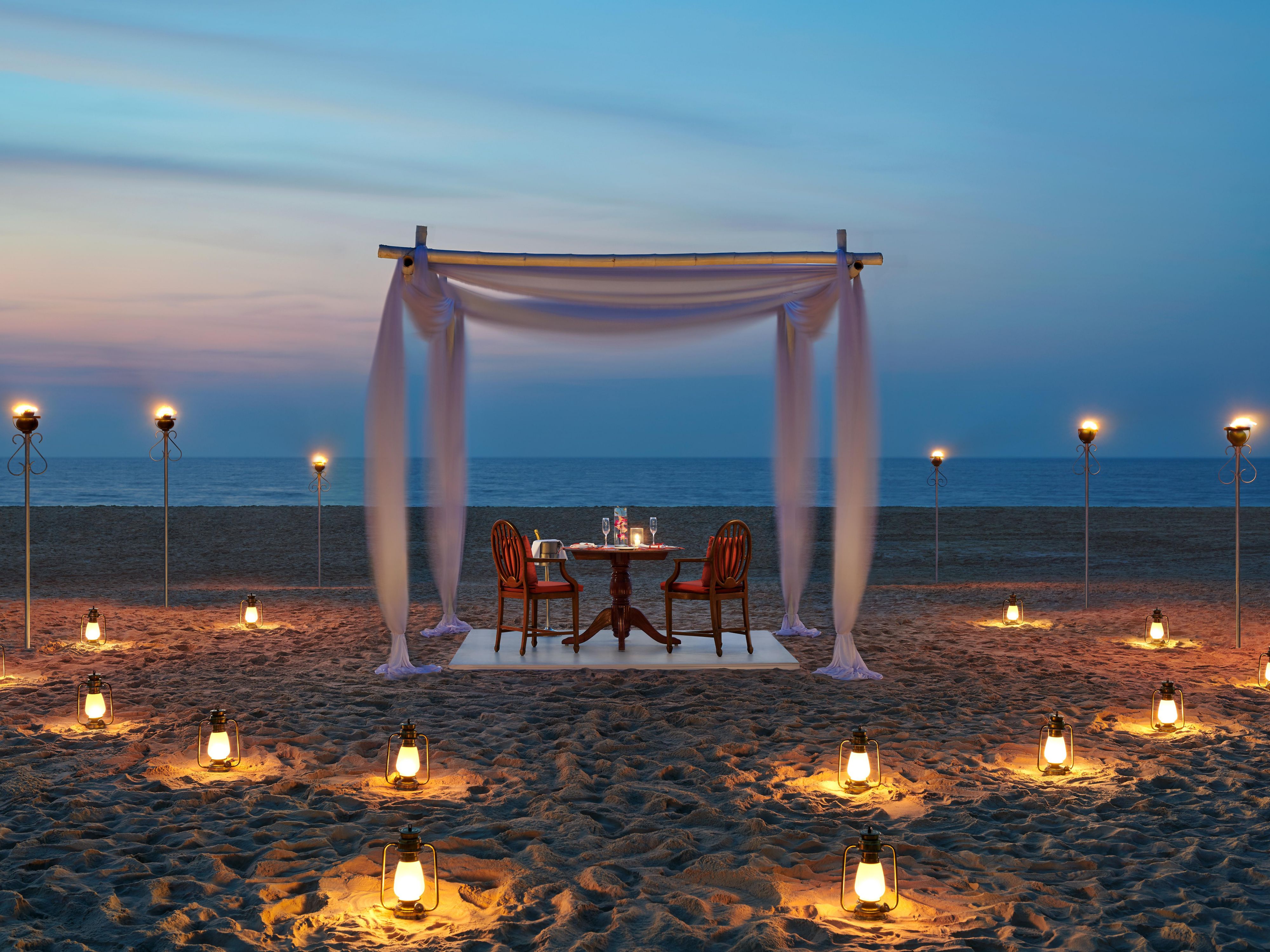 An elegant table, exquisite and delectable cuisine paired with fine wine, candlelight, and that special someone—everything you need for a perfect evening by the beach on pristine white sand. This romantic setup is sure to make your vacation unforgettable.