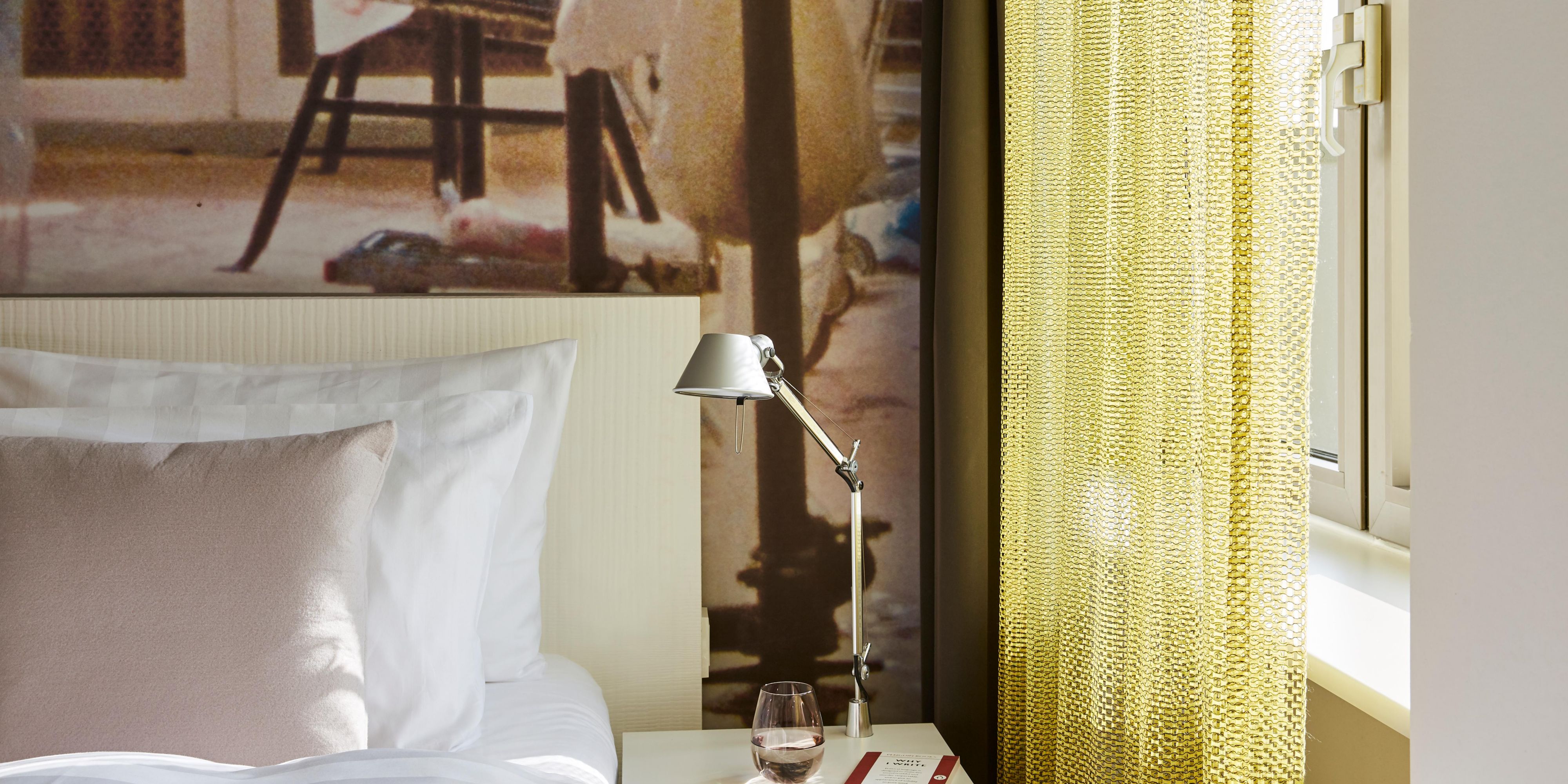 A guest room with a double bed and funky wall print.