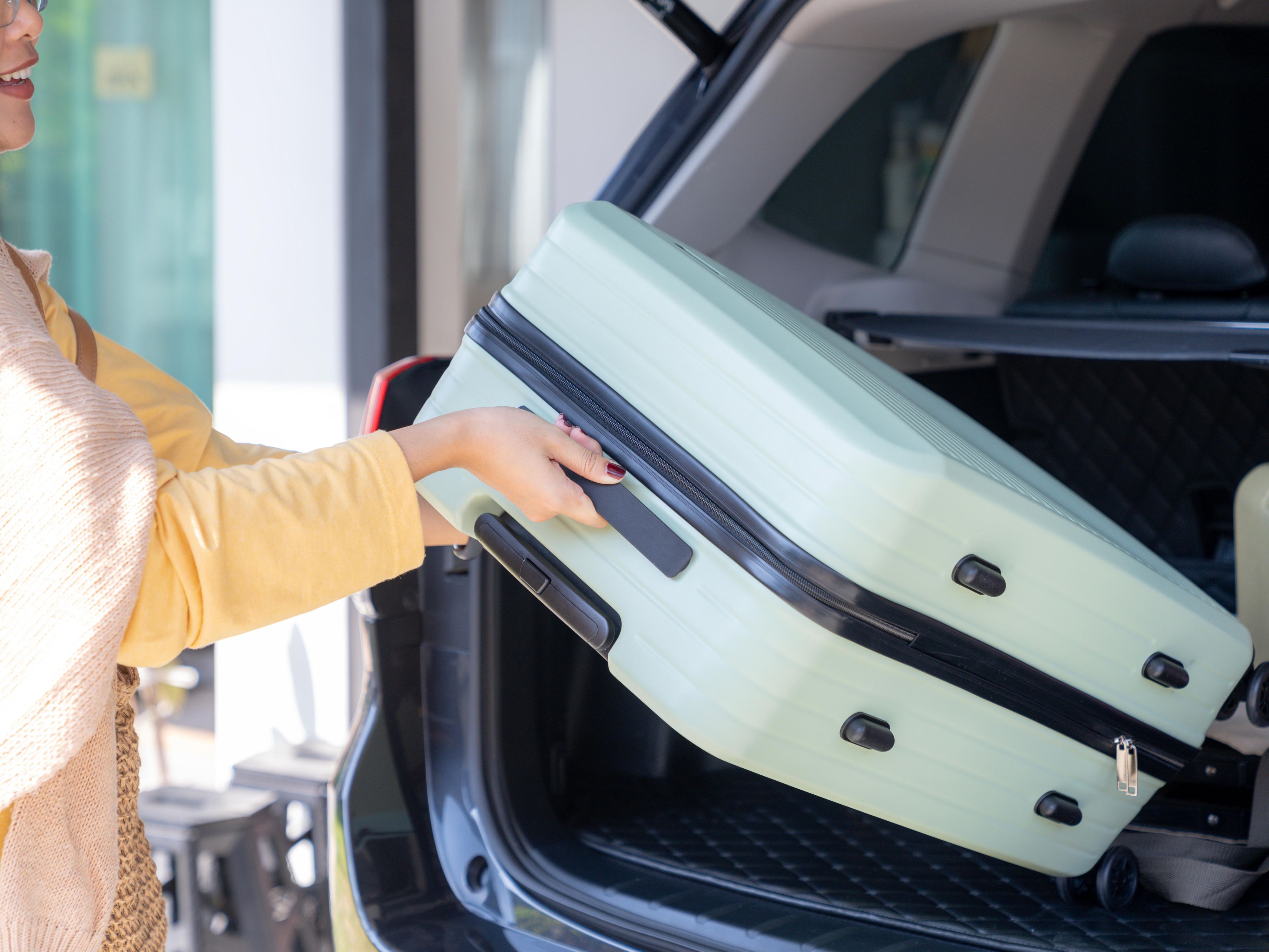 woman pulling suitecase out of car