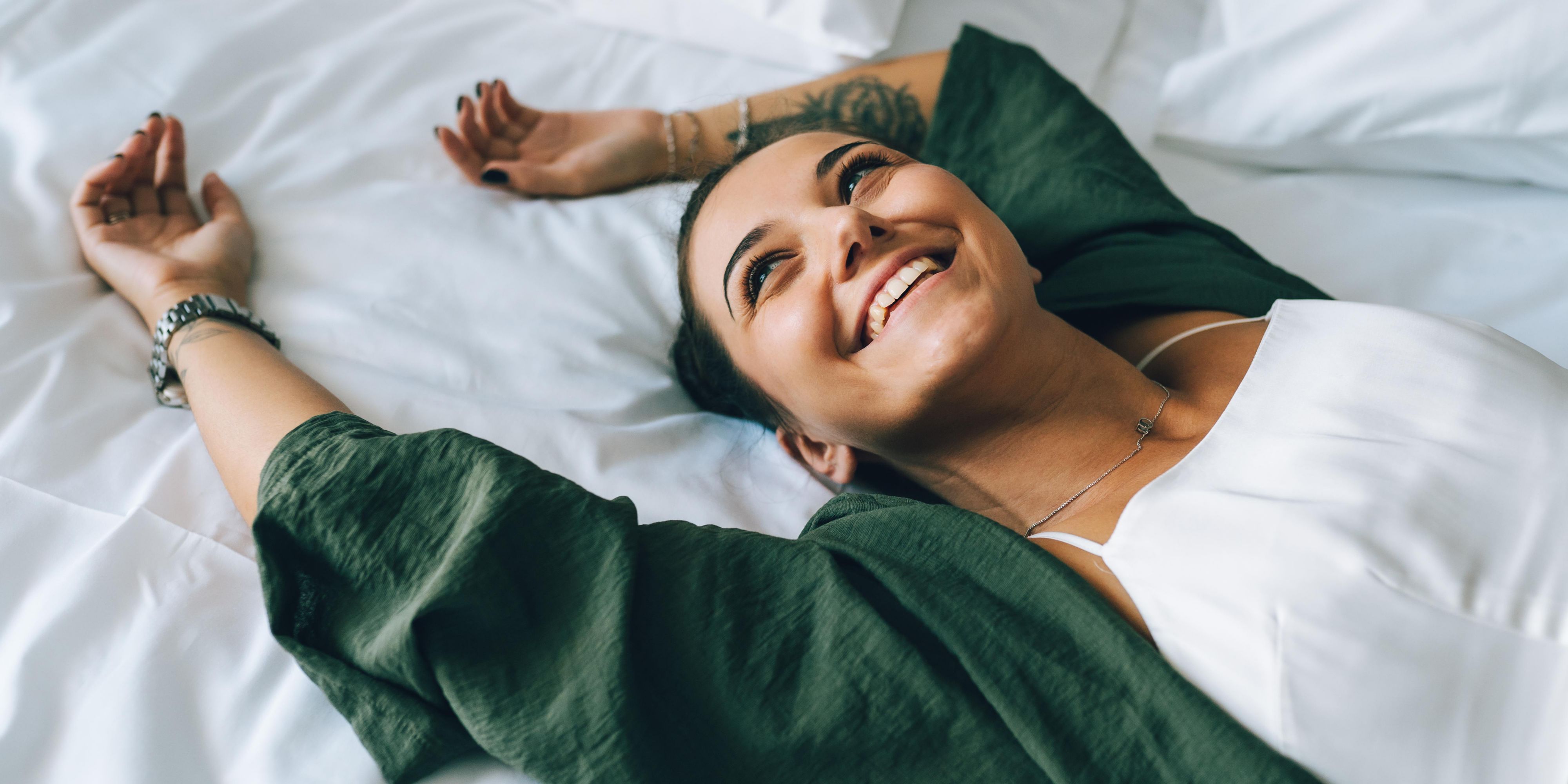 woman lying on a hotel guest bed smiling