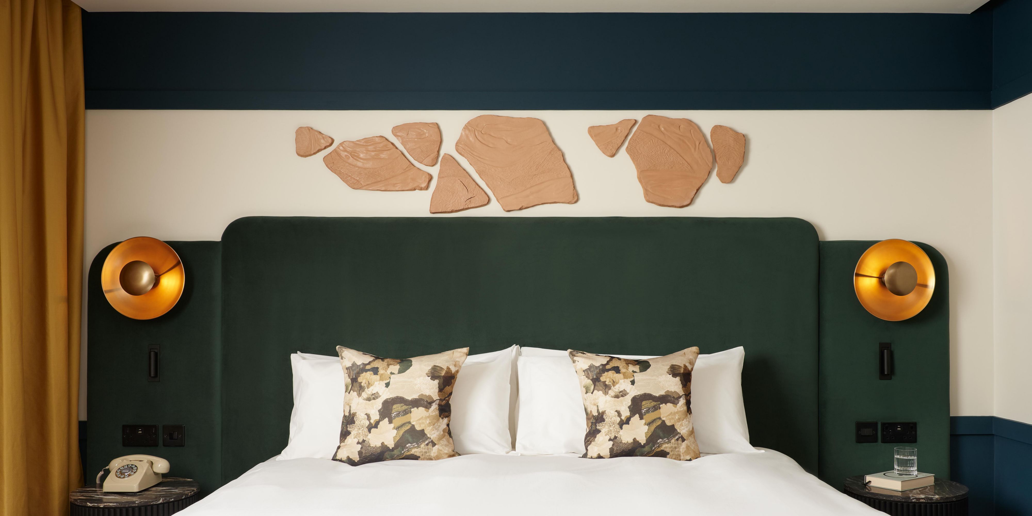 hotel guest bedroom with green backdrop bed, and wall handings