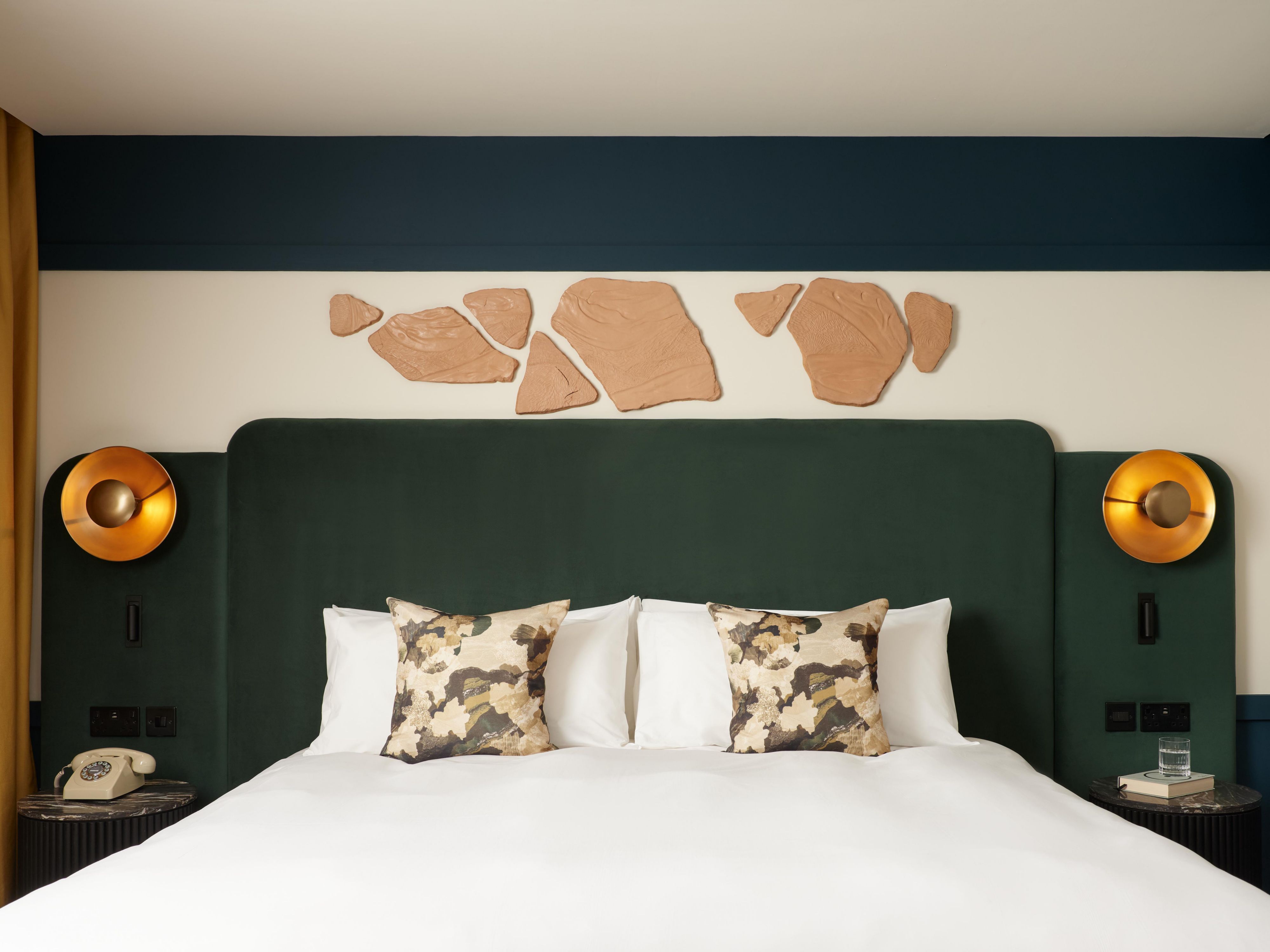 hotel guest bedroom with green bed, wall decorations and city views