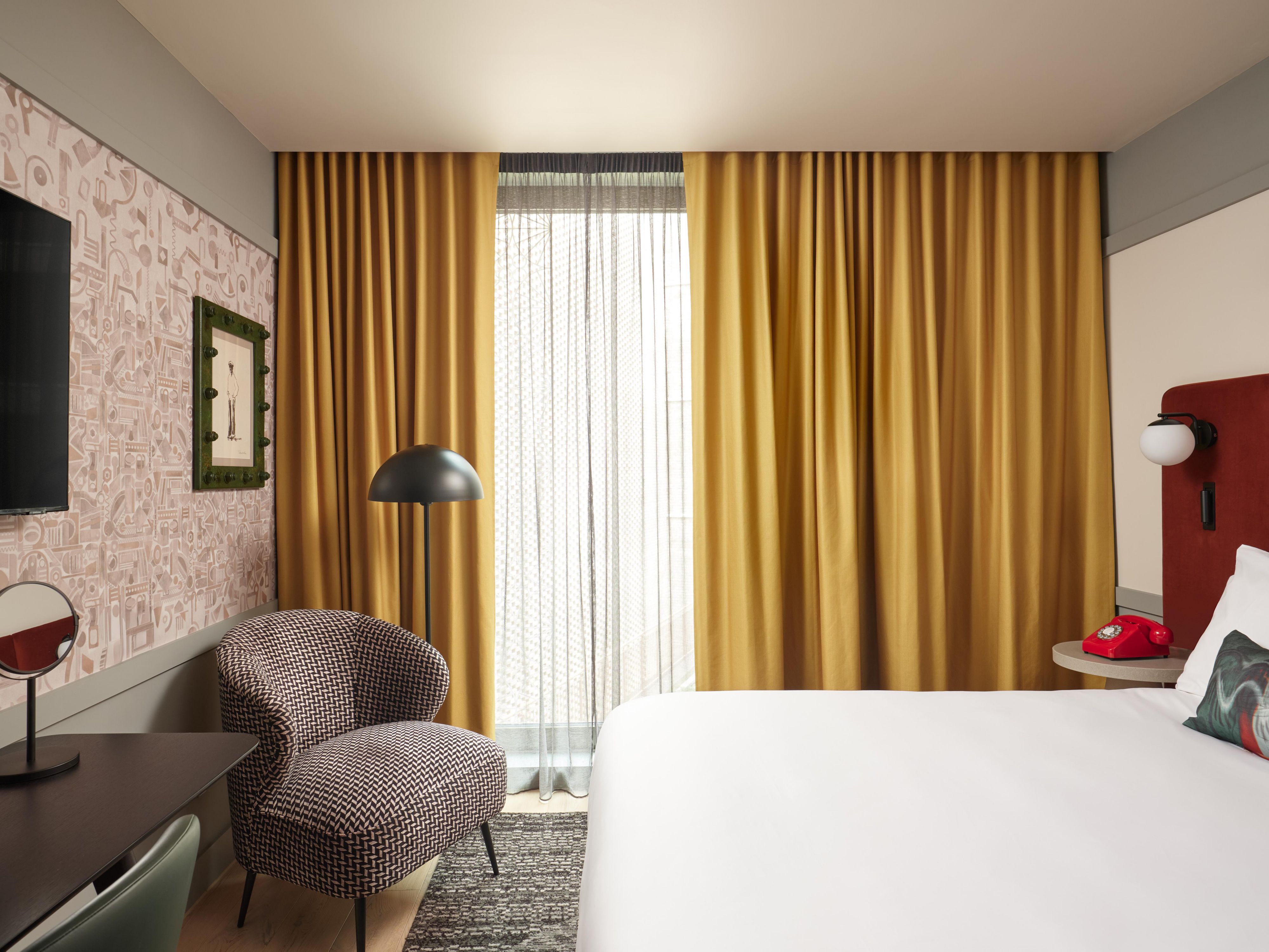 hotel guest rooms with red bed, british telephone, large windows and cosy chair
