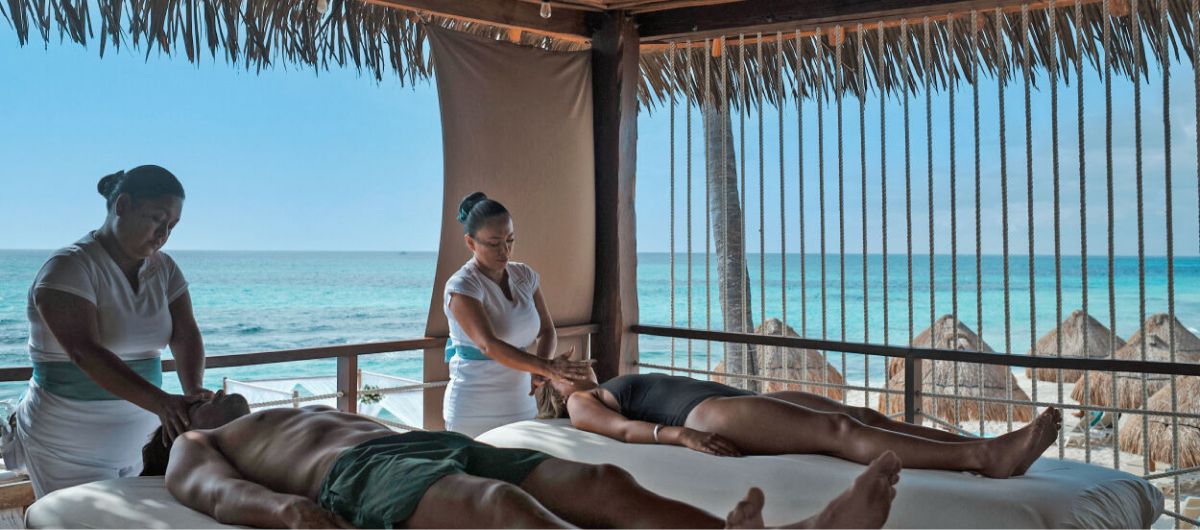 An oceanside couples massage in an outdoor beachfront cabana.
