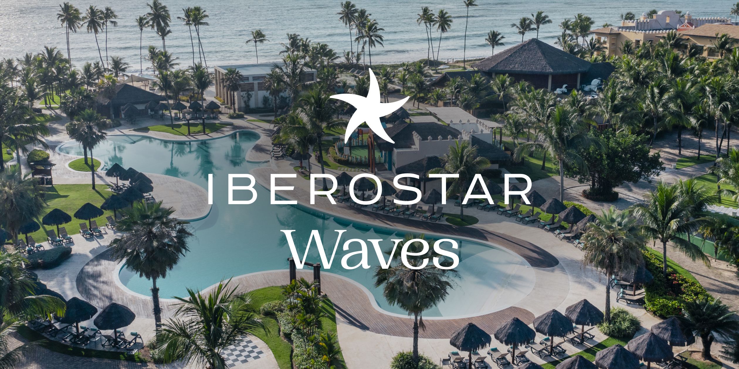 A pool near the ocean surrounded by palm trees at Iberostar Waves.