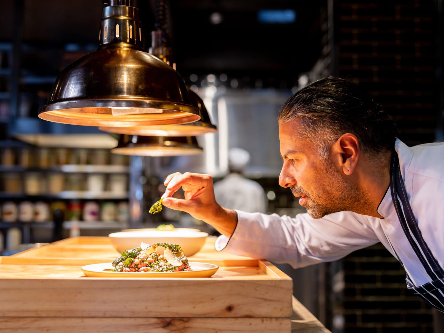 chef puts finishing garnish on a plate