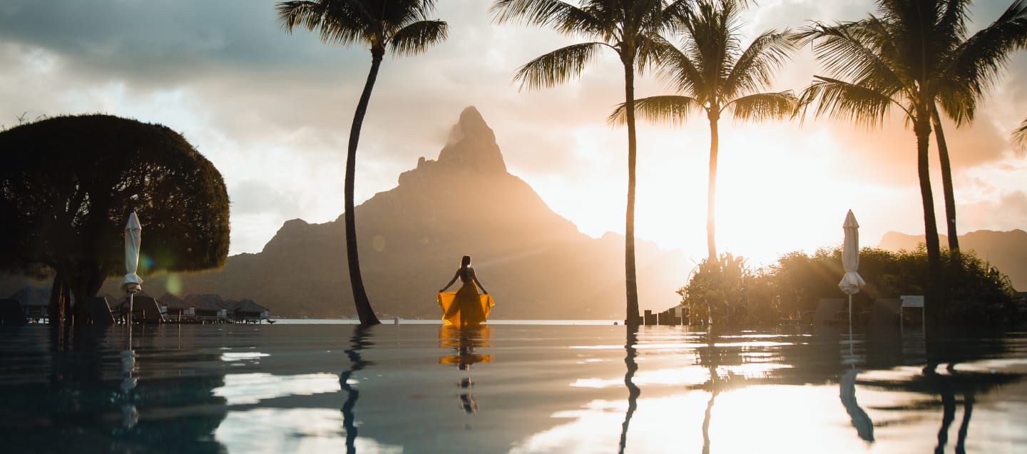 woman walking in sea among palm trees
