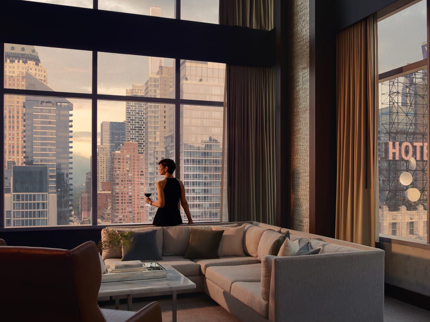 woman in a suite overlooking a city with a glass of wine