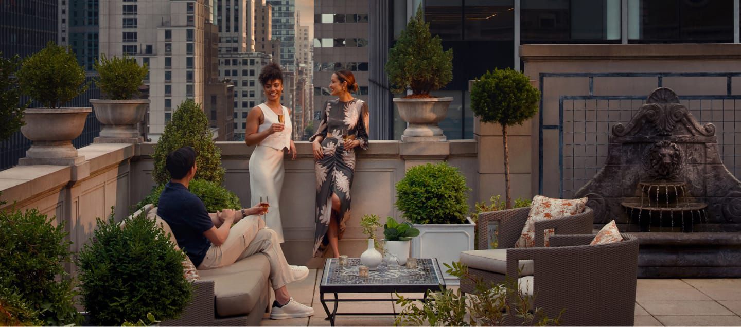 人们站在屋顶石砌露台上，欣赏城市美景