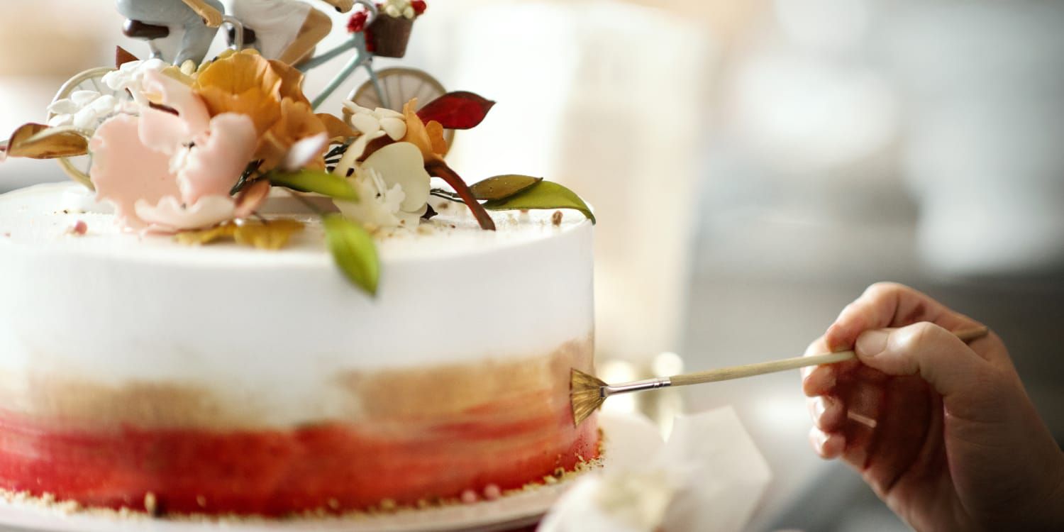 painting gold onto an elaborate artful wedding cake