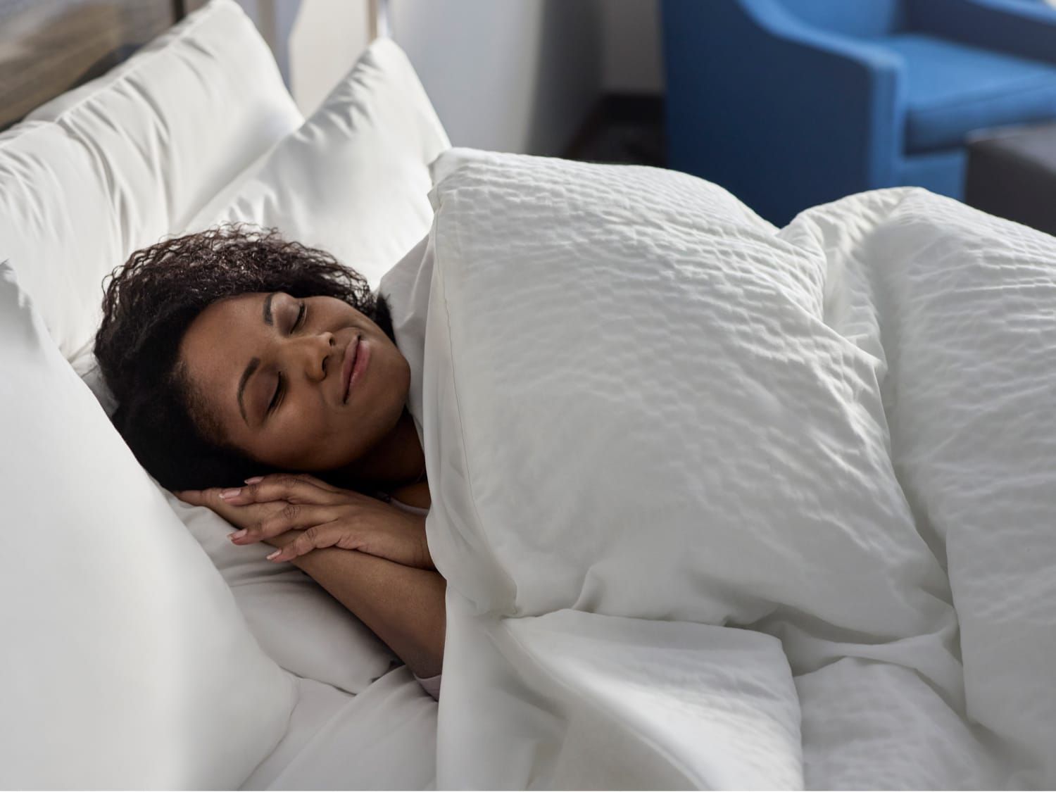 一位女士在 Garner 酒店的奢华床上安然入睡。