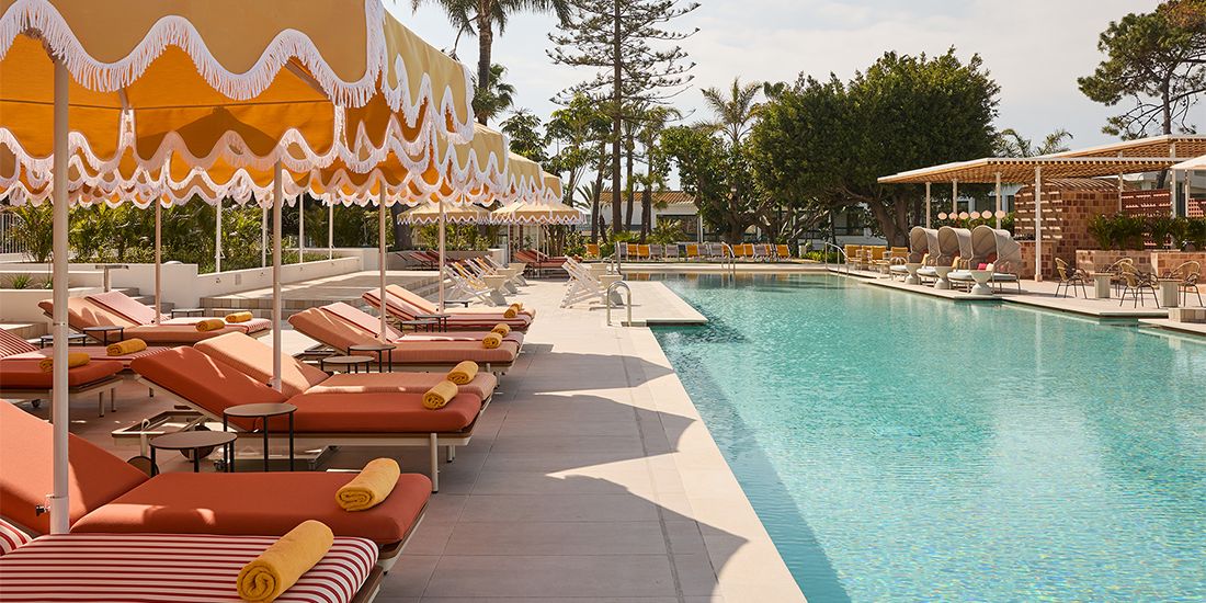 四周环绕着躺椅和遮阳伞的泳池