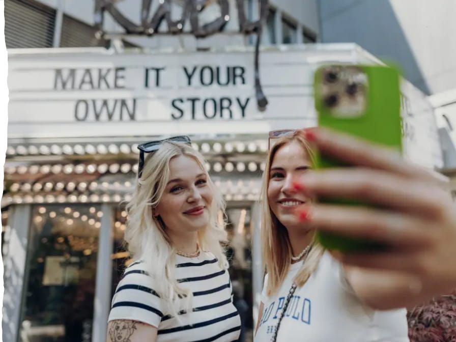 两位女士在“书写专属故事”的标牌前自拍