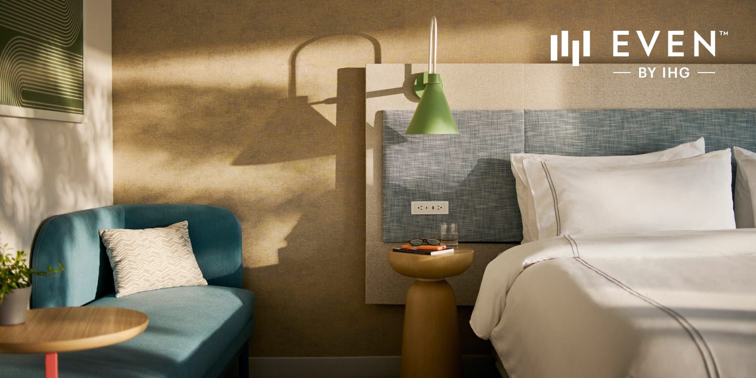 Modern hotel room with crisp white bedding and shadows cast on the wall.