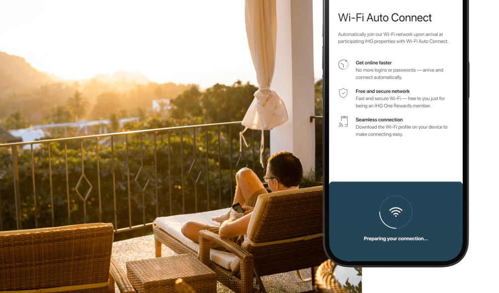 Man lounging on balcony using phone, IHG app wi-fi auto connect on phone screen