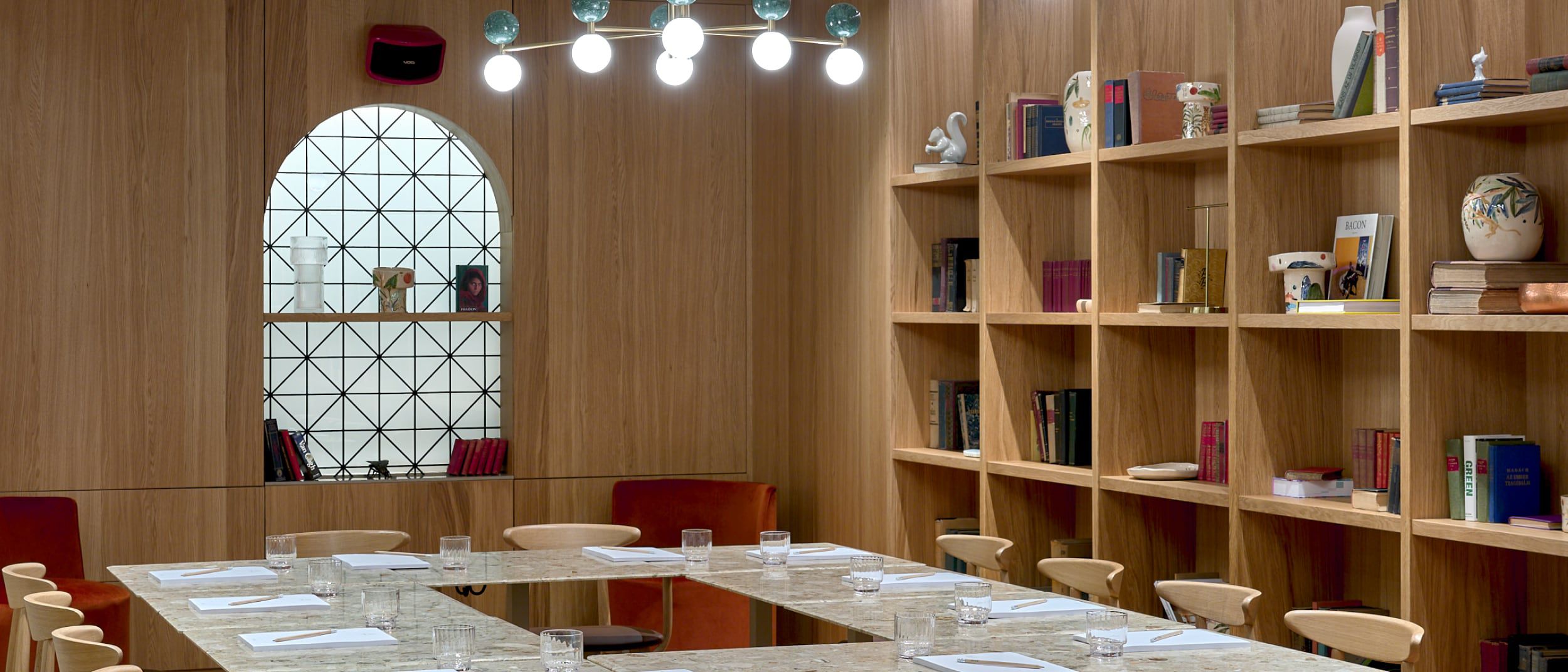 A library-like meeting room with a marble table and diamond-paned windows