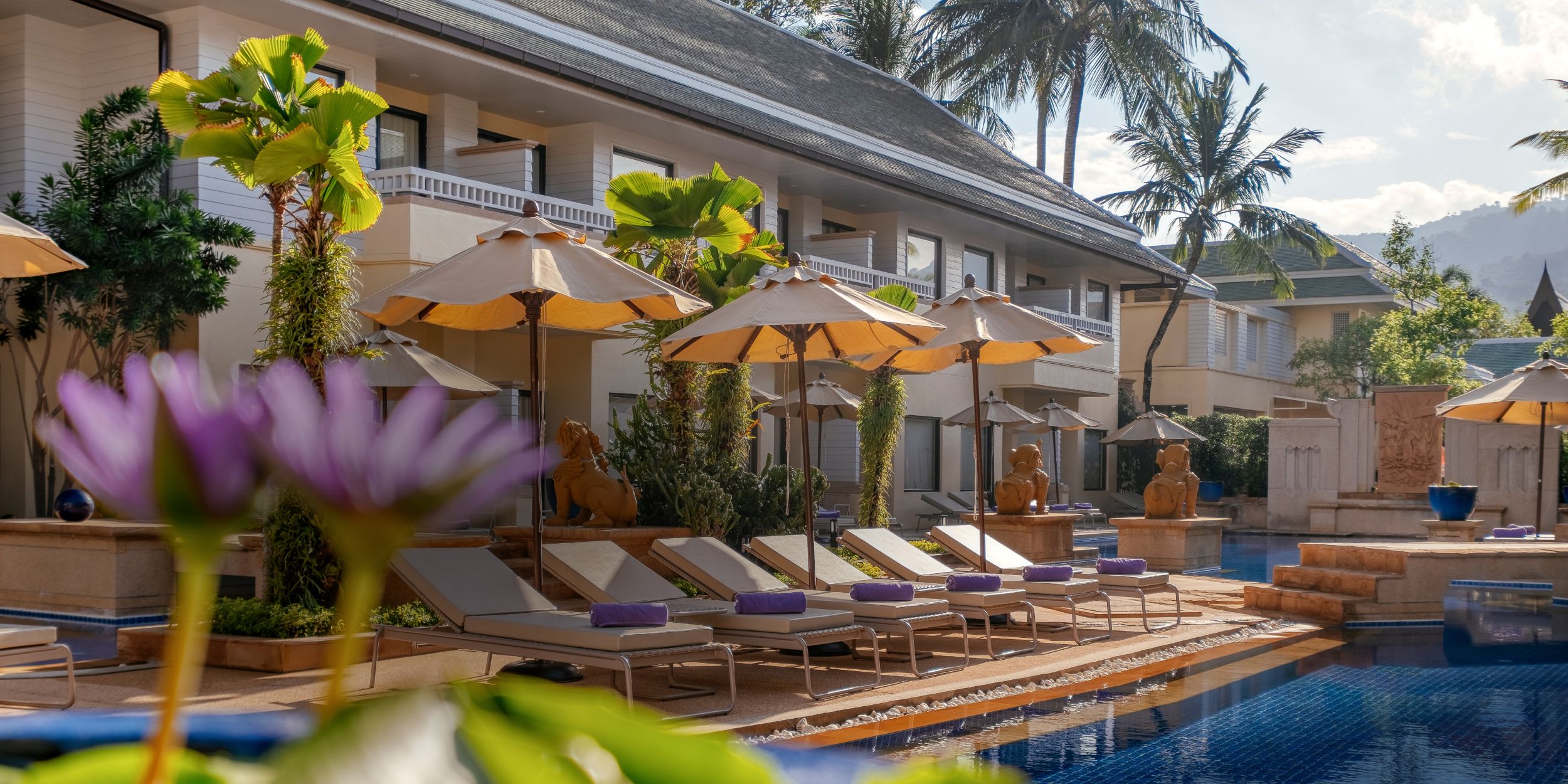 A poolside scene with sun loungers, umbrellas and Holiday Inn Resort Phuket in the background.