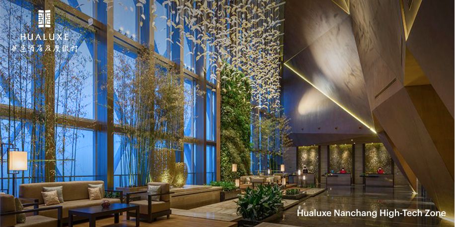 The bright, open lobby of the Hualuxe Nanchang, featuring dramatically high ceilings, bamboo planters, and an art installation featuring paper birds. 