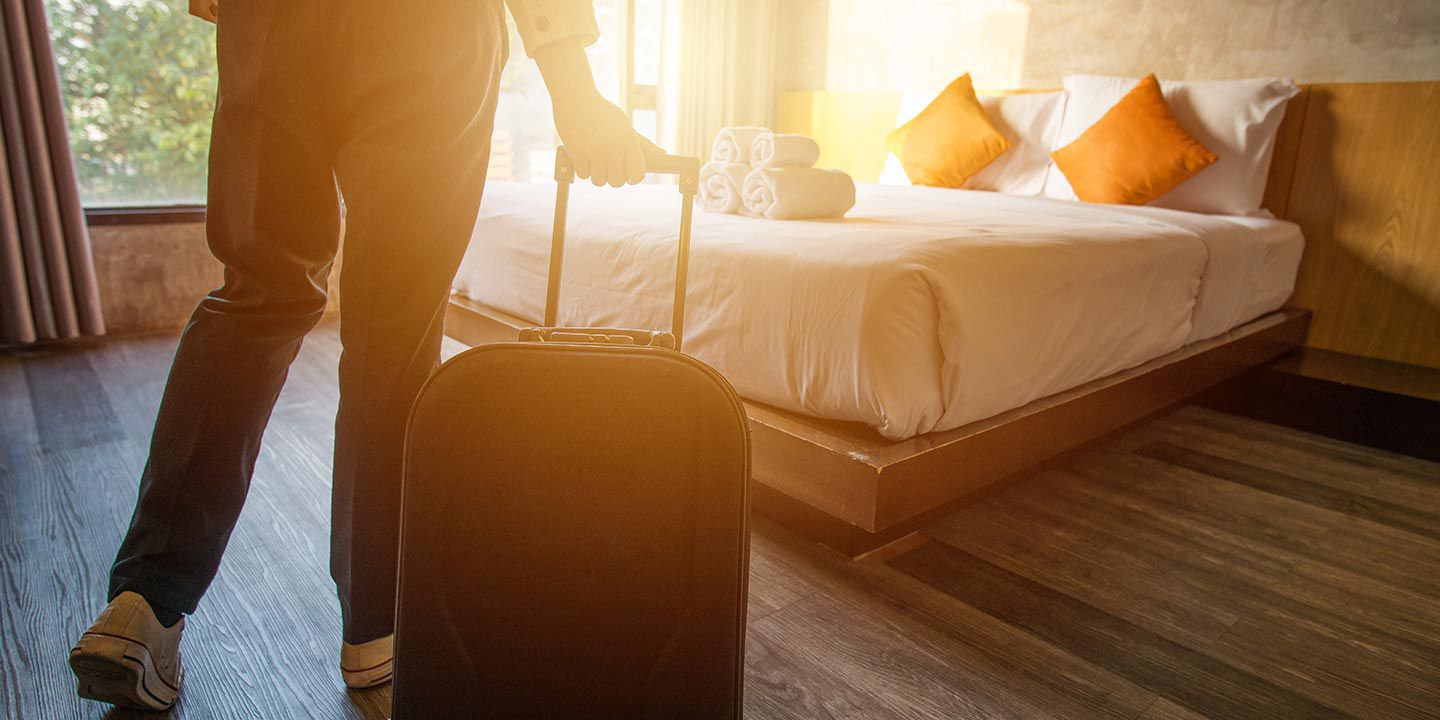 Person rolling suitcase into hotel room 