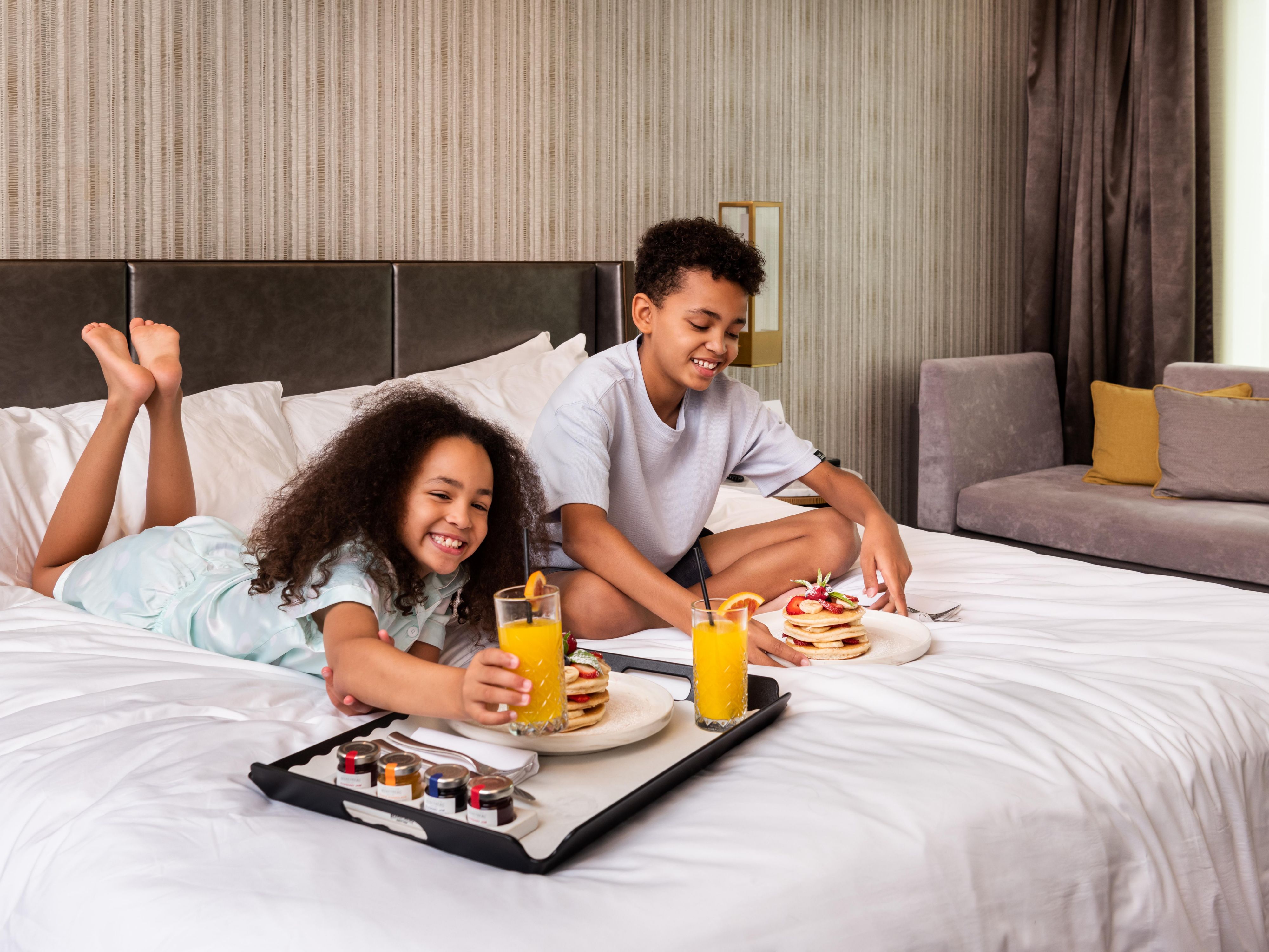 Children enjoying room service on the hotel bed