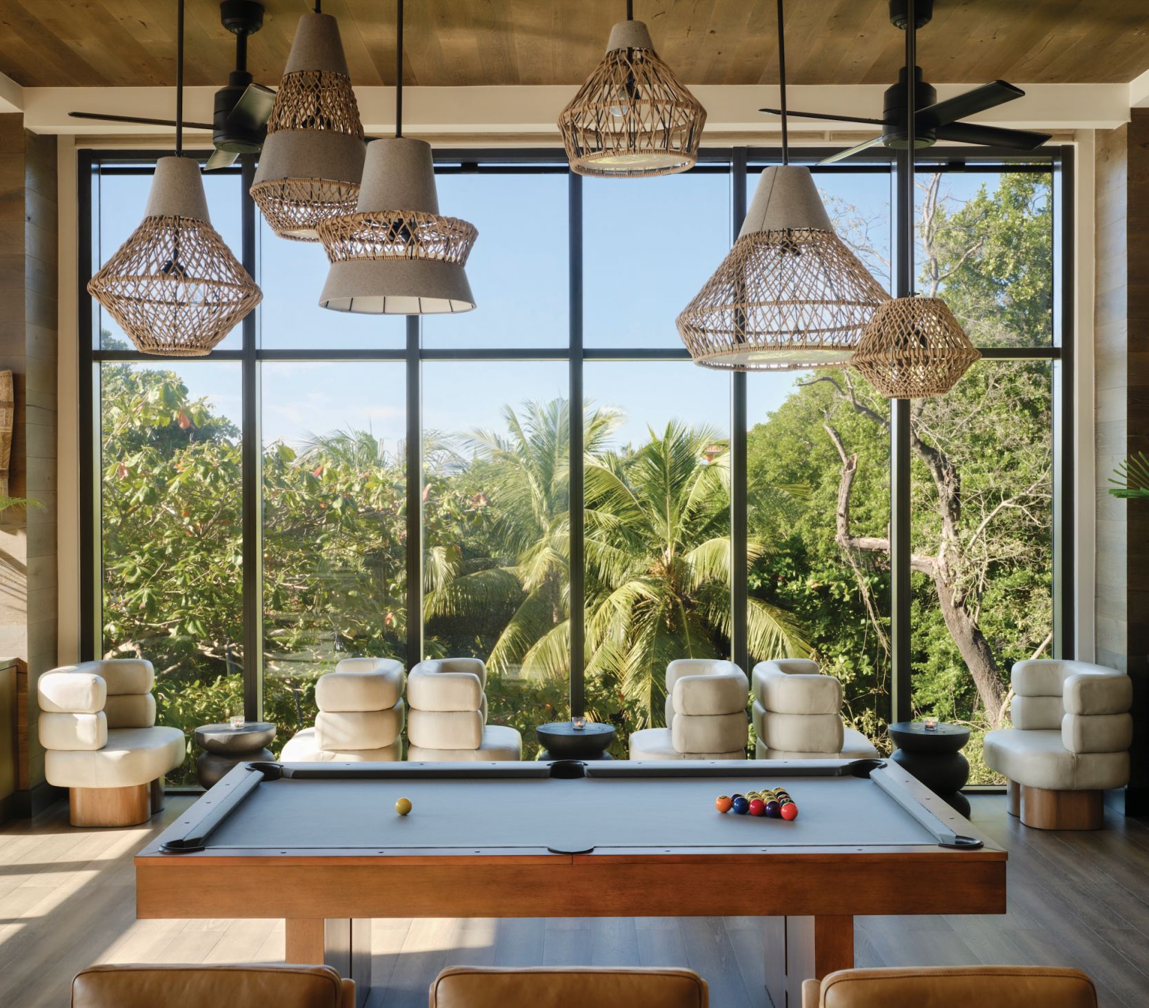 pool table, modern chairs, floor to ceiling windows overlooking tropical lush environment